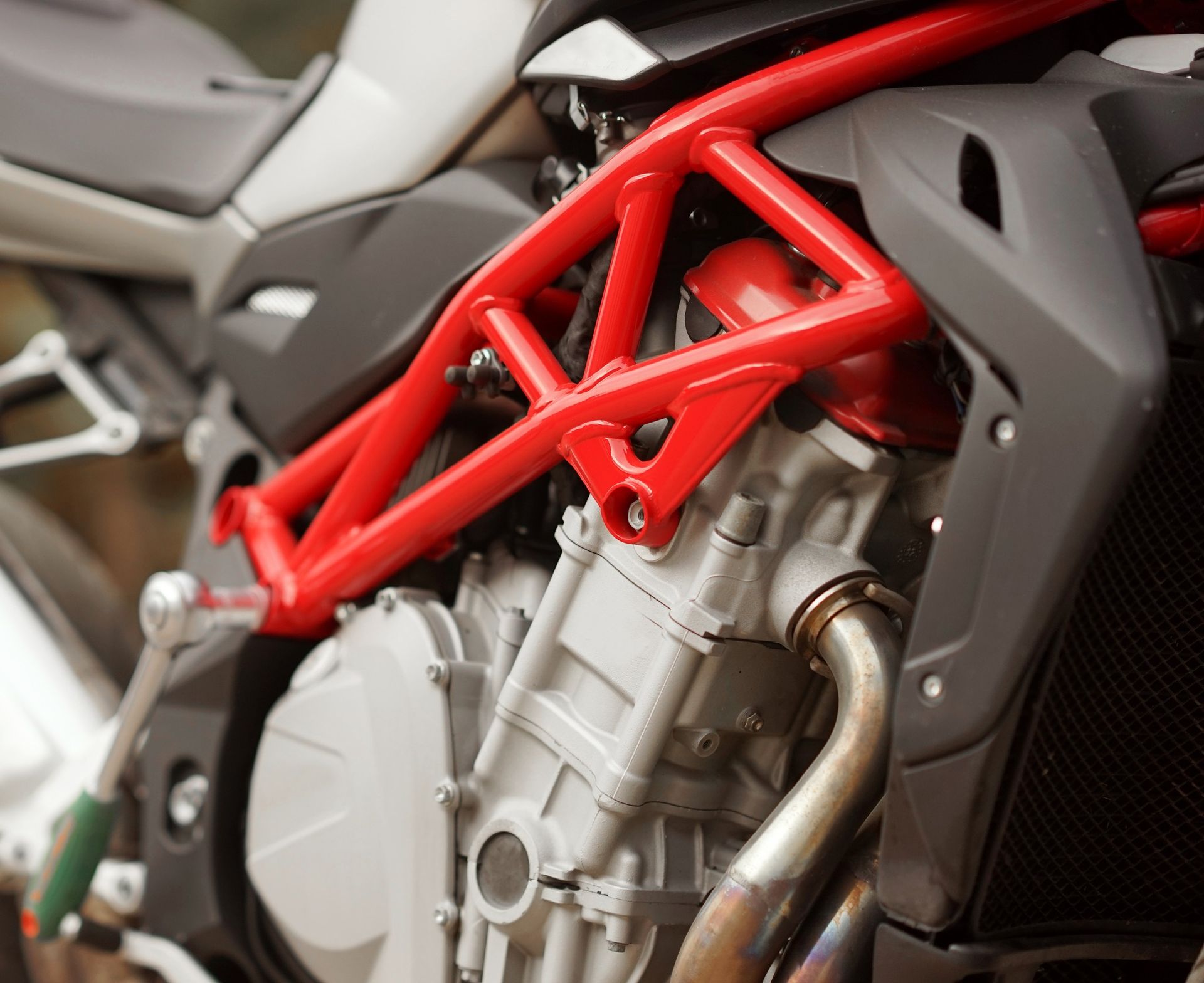 Close-up of a red motorcycle frame and silver engine with a black fairing detail