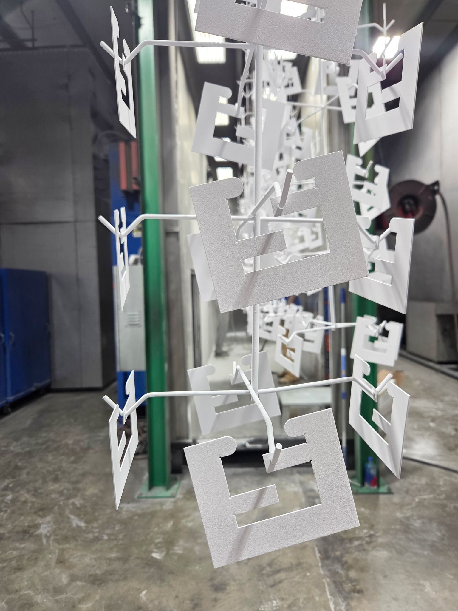 Hanging silver paper craft with square cutouts in an indoor workshop or studio