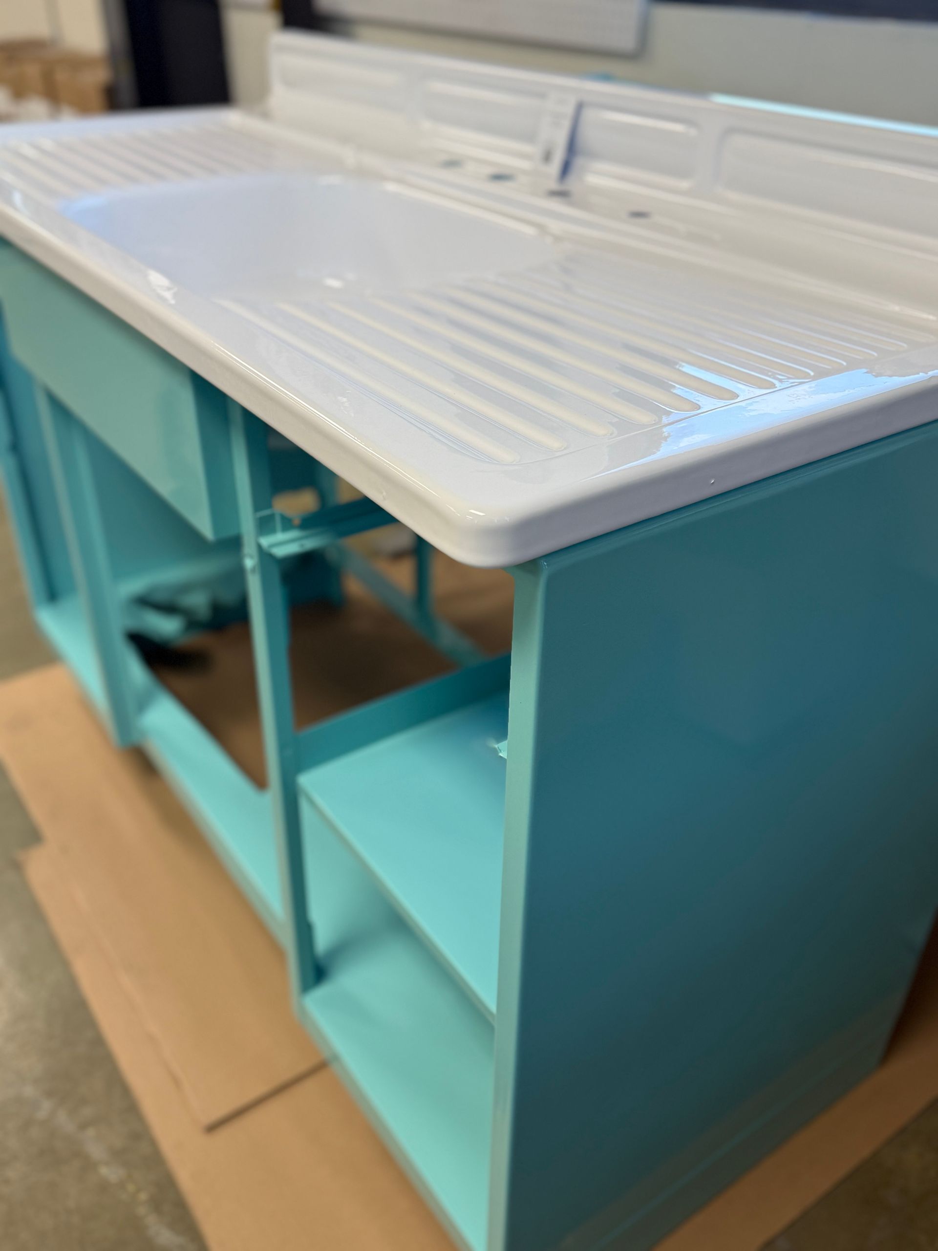 Turquoise kitchen island with white ribbed countertop on a wooden floor, viewed at an angle