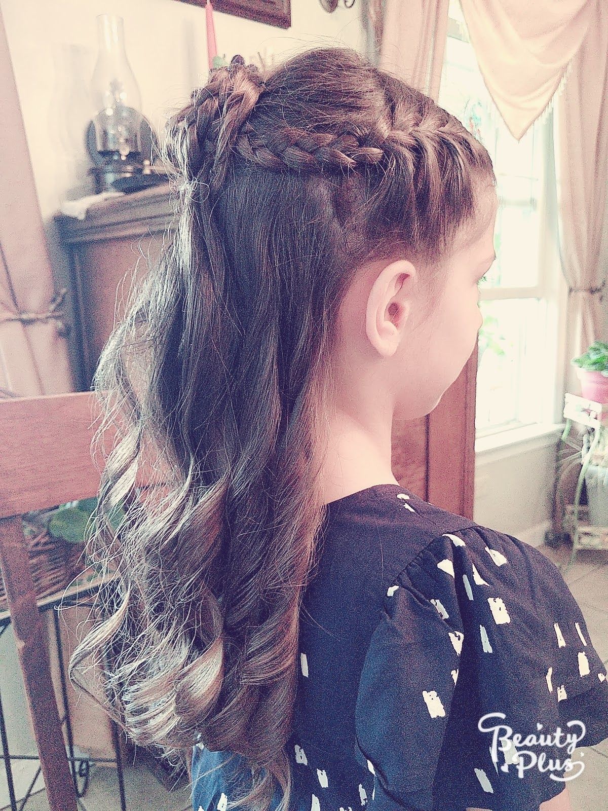 a little girl with long hair is wearing a braided ponytail