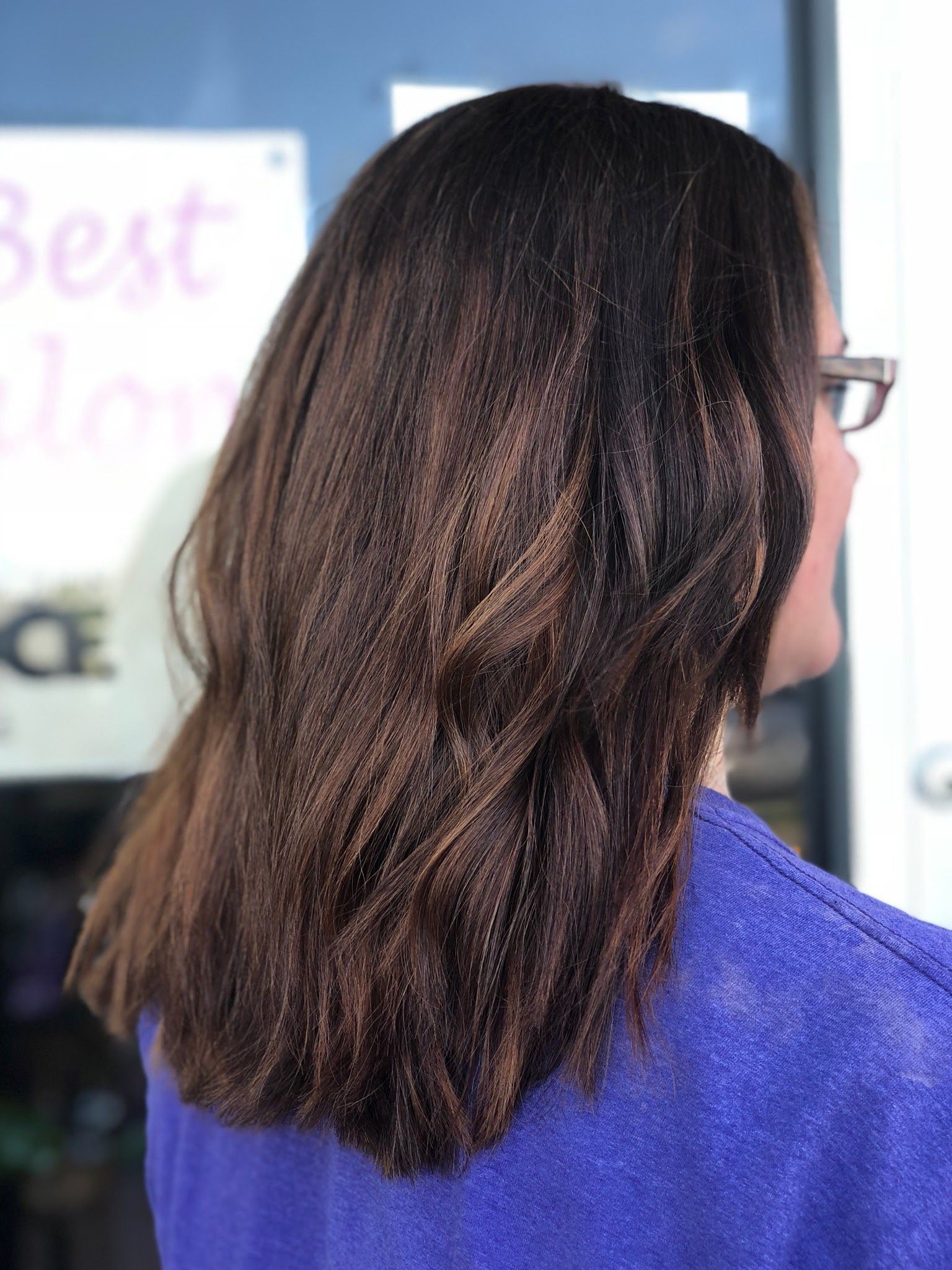 a woman with long brown hair is wearing glasses and a blue shirt