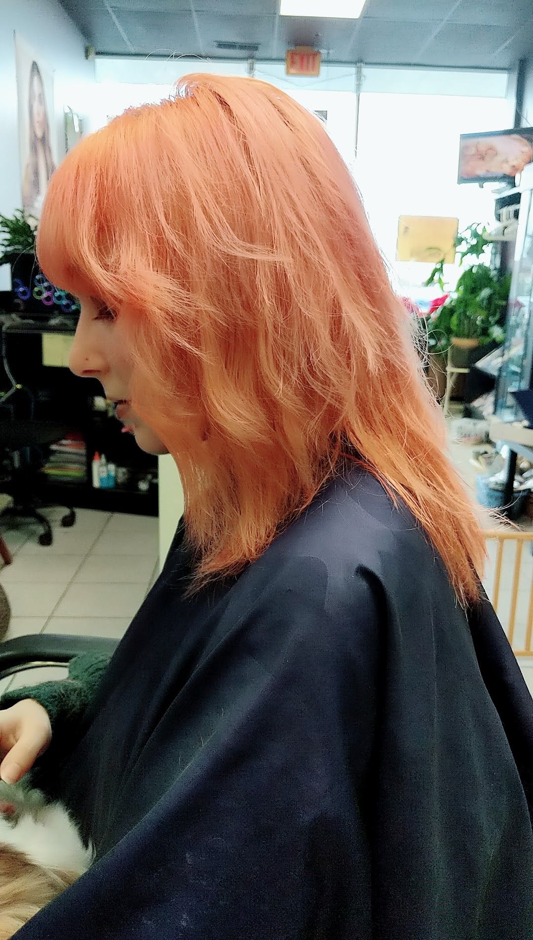 a woman with orange hair is getting her hair cut in a salon