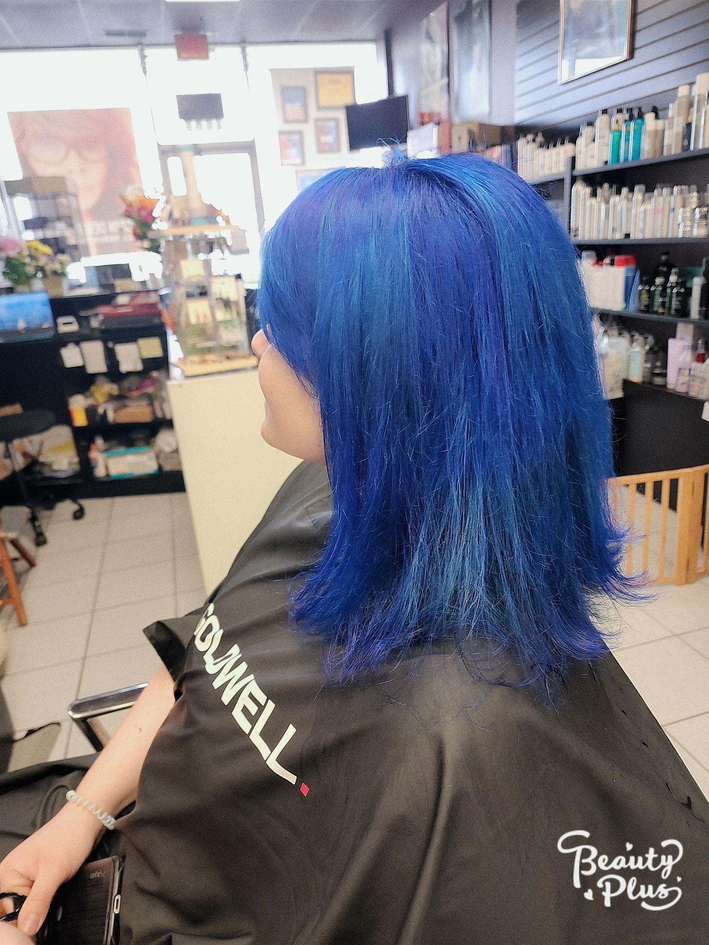 a woman with blue hair is getting her hair cut