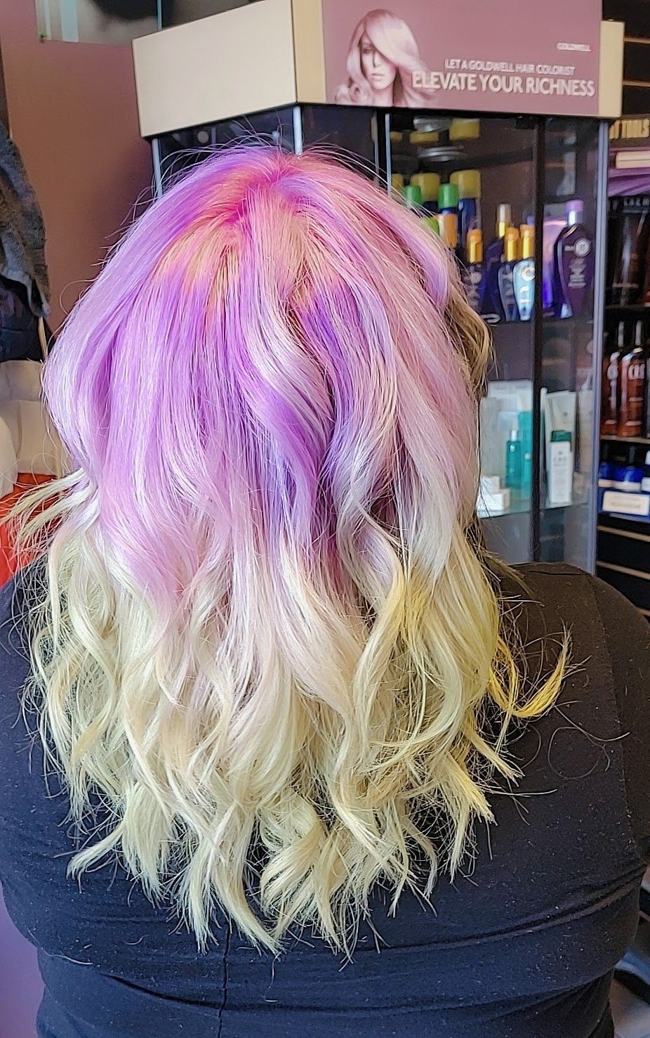 a woman with purple and blonde hair is sitting in a salon 