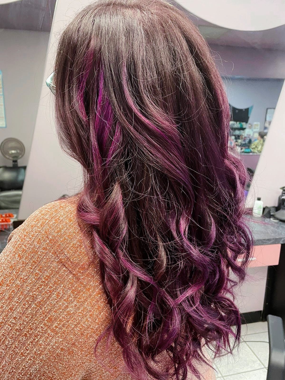 a woman with purple highlights is sitting in a salon