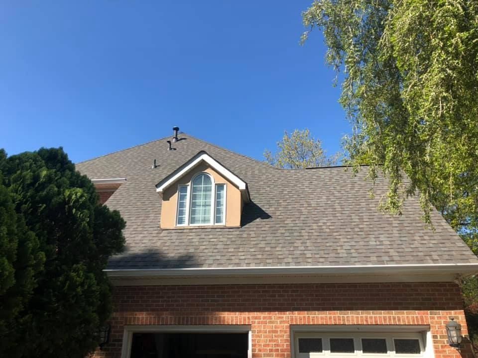 A brick house with a roof that has a window on it.