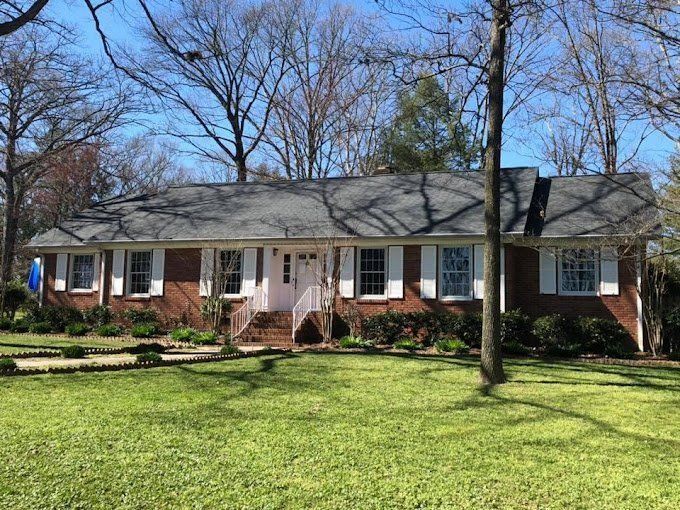 A large brick house with a black roof and white shutters