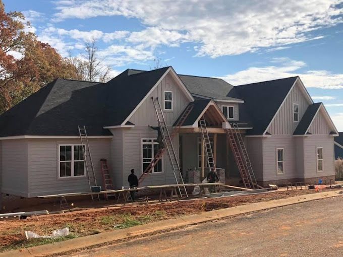 A large white house with a black roof is being built.
