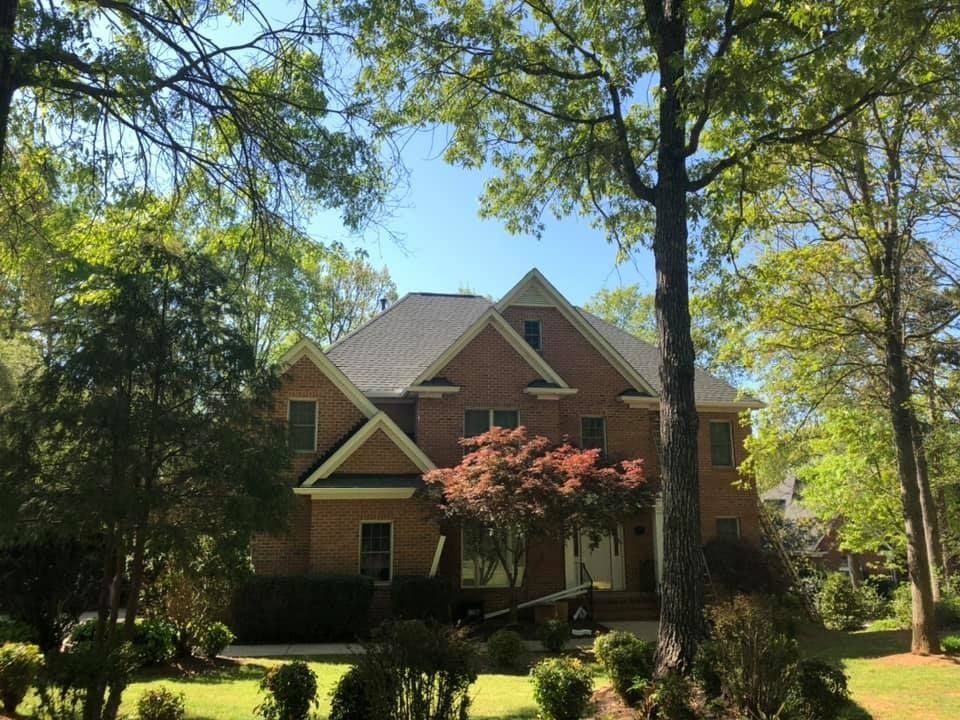 A large brick house surrounded by trees on a sunny day