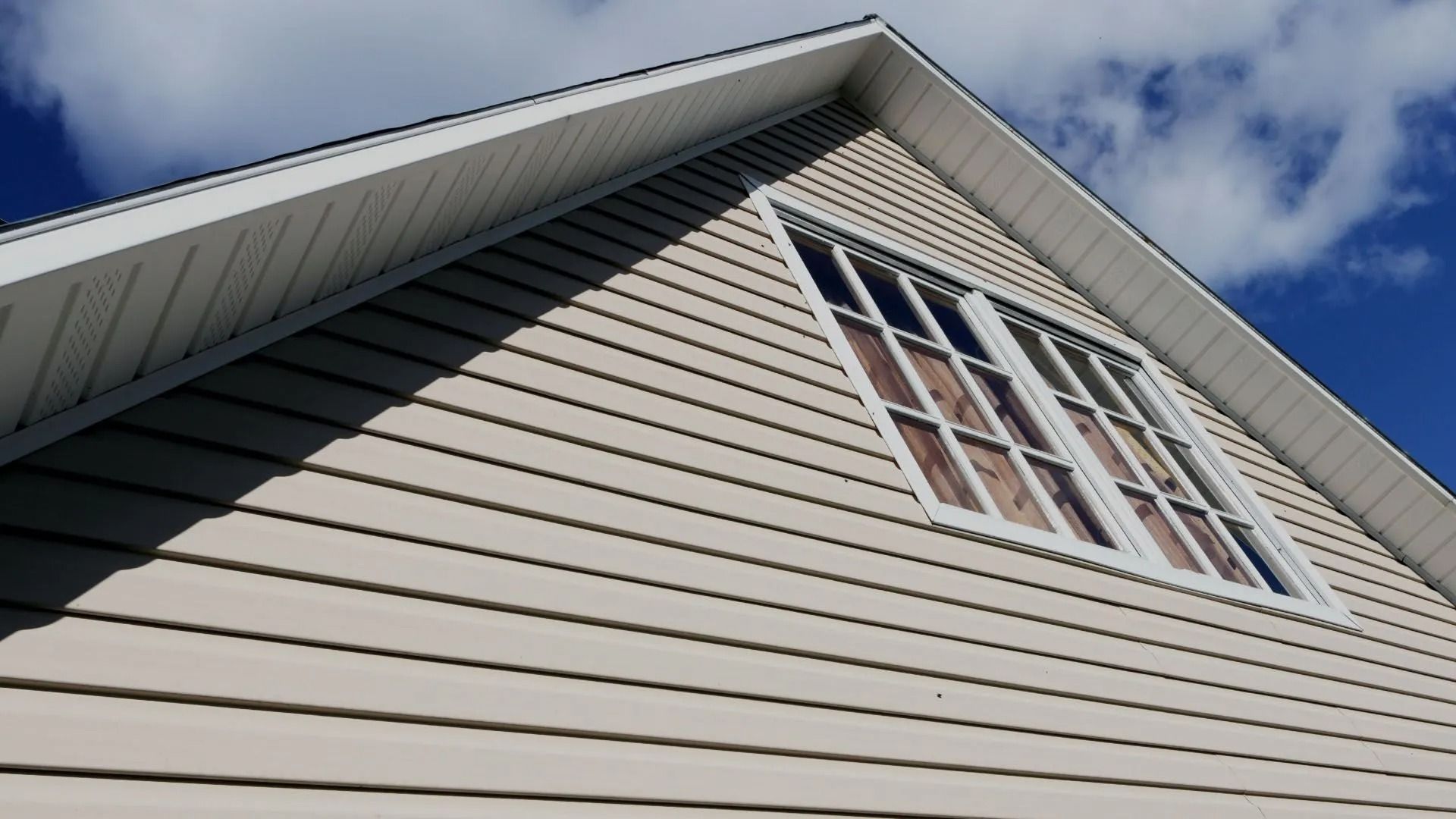 Looking up at the roof of a house with a blue sky in the background