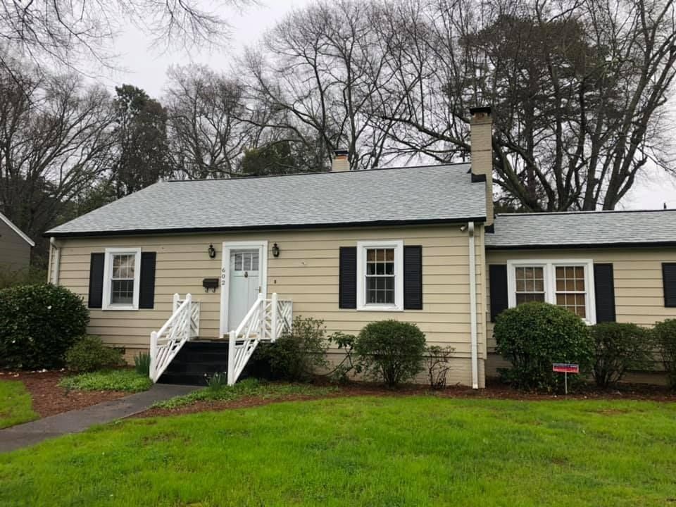 A house with a gray roof and black shutters is for sale.