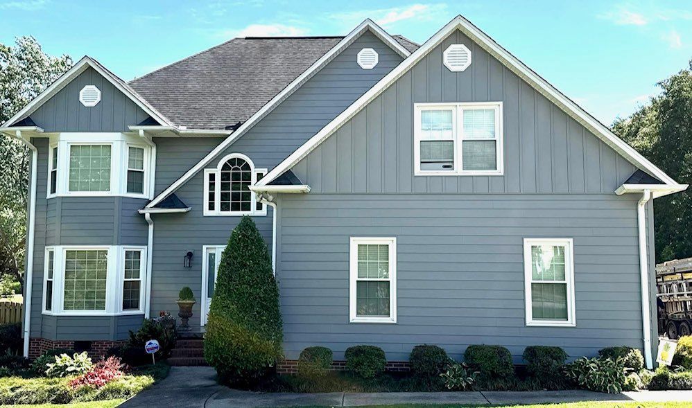 Gray two-story house with white trim, multiple gables, and landscaping.