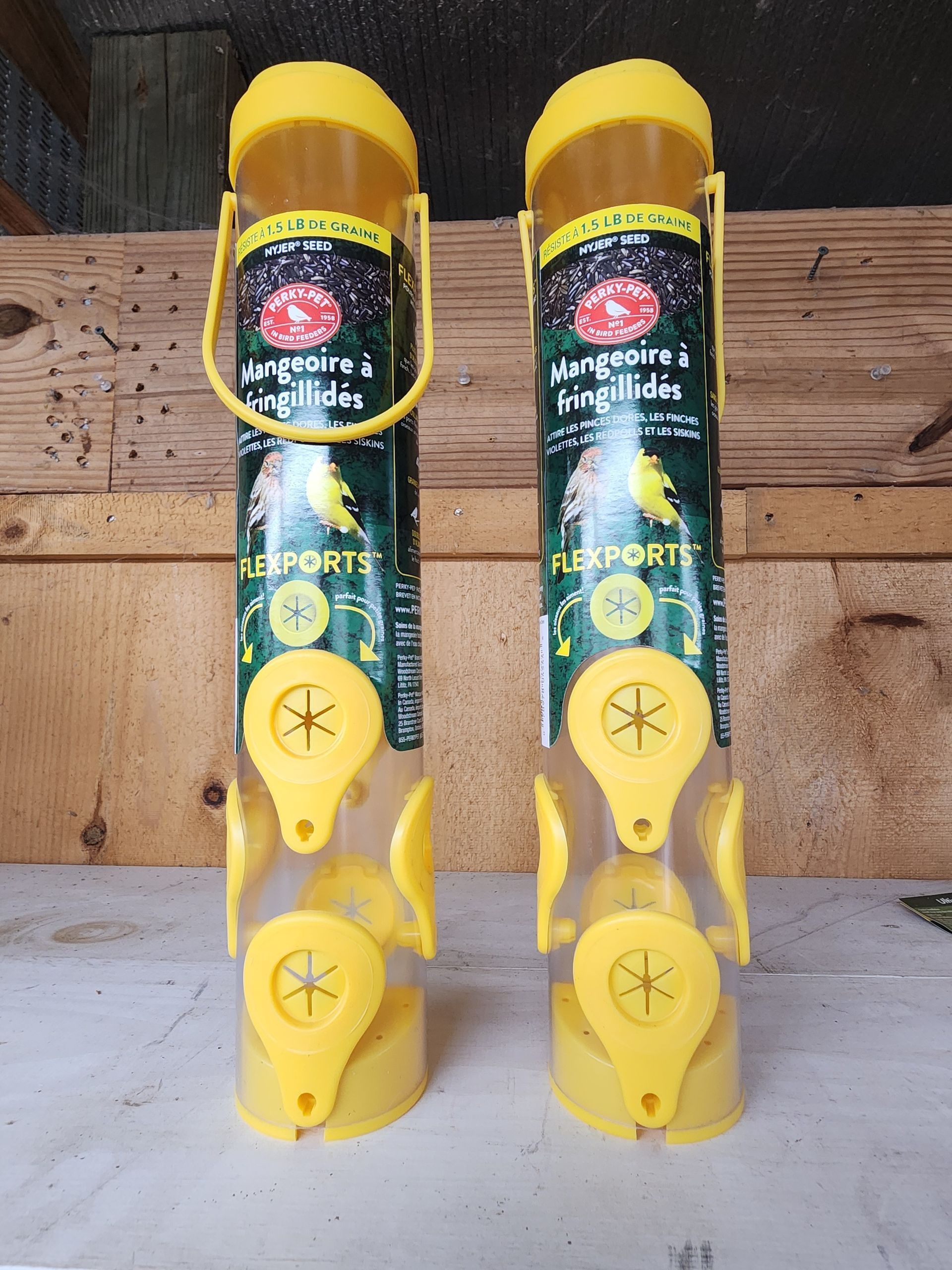 Two yellow mosquito traps standing upright against a wooden wall.