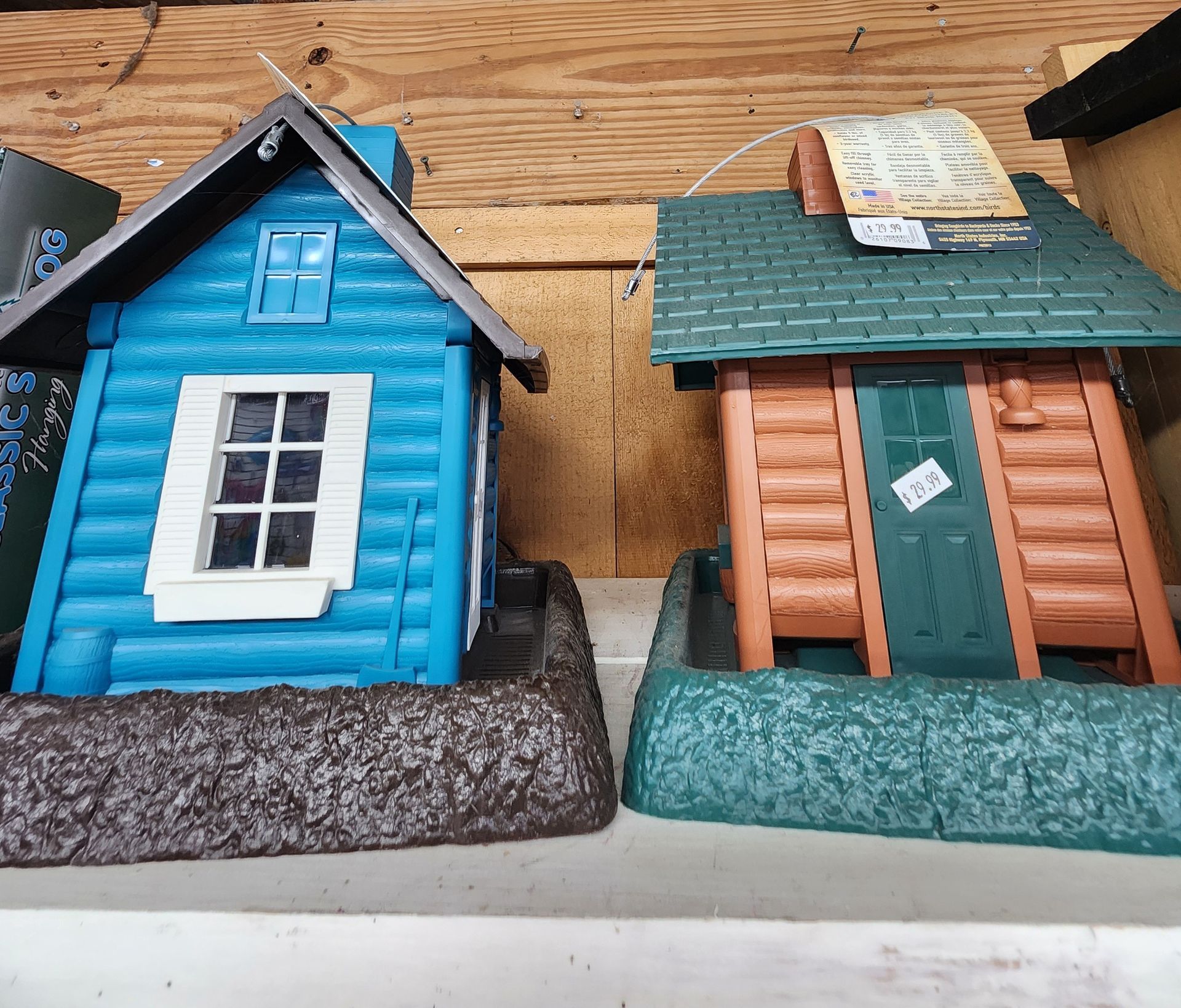 Two colorful model houses: blue with white trim and tan with green roof on a wooden surface.