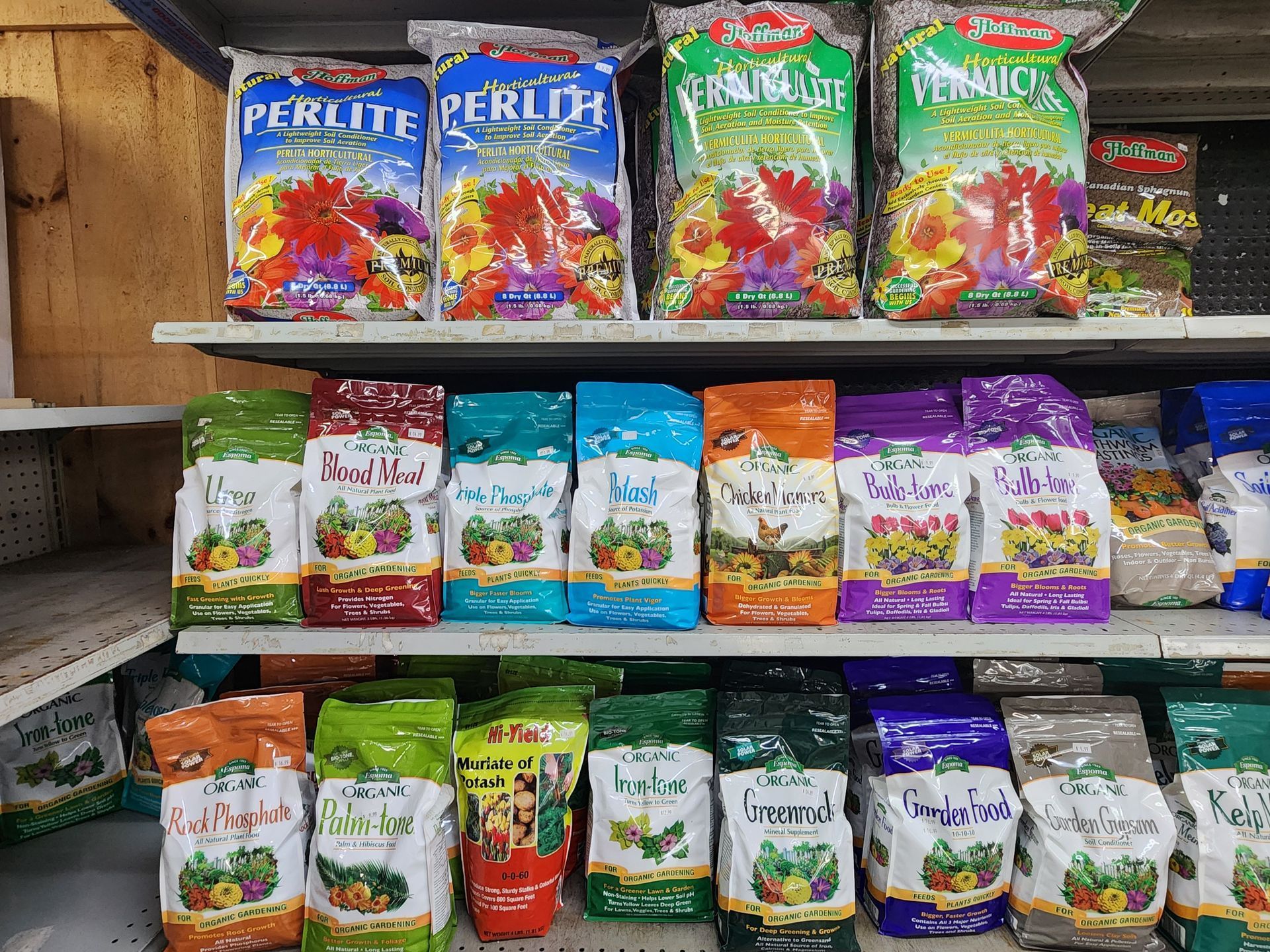 Shelves of colorful bags of potting mix and plant soil in a garden center aisle