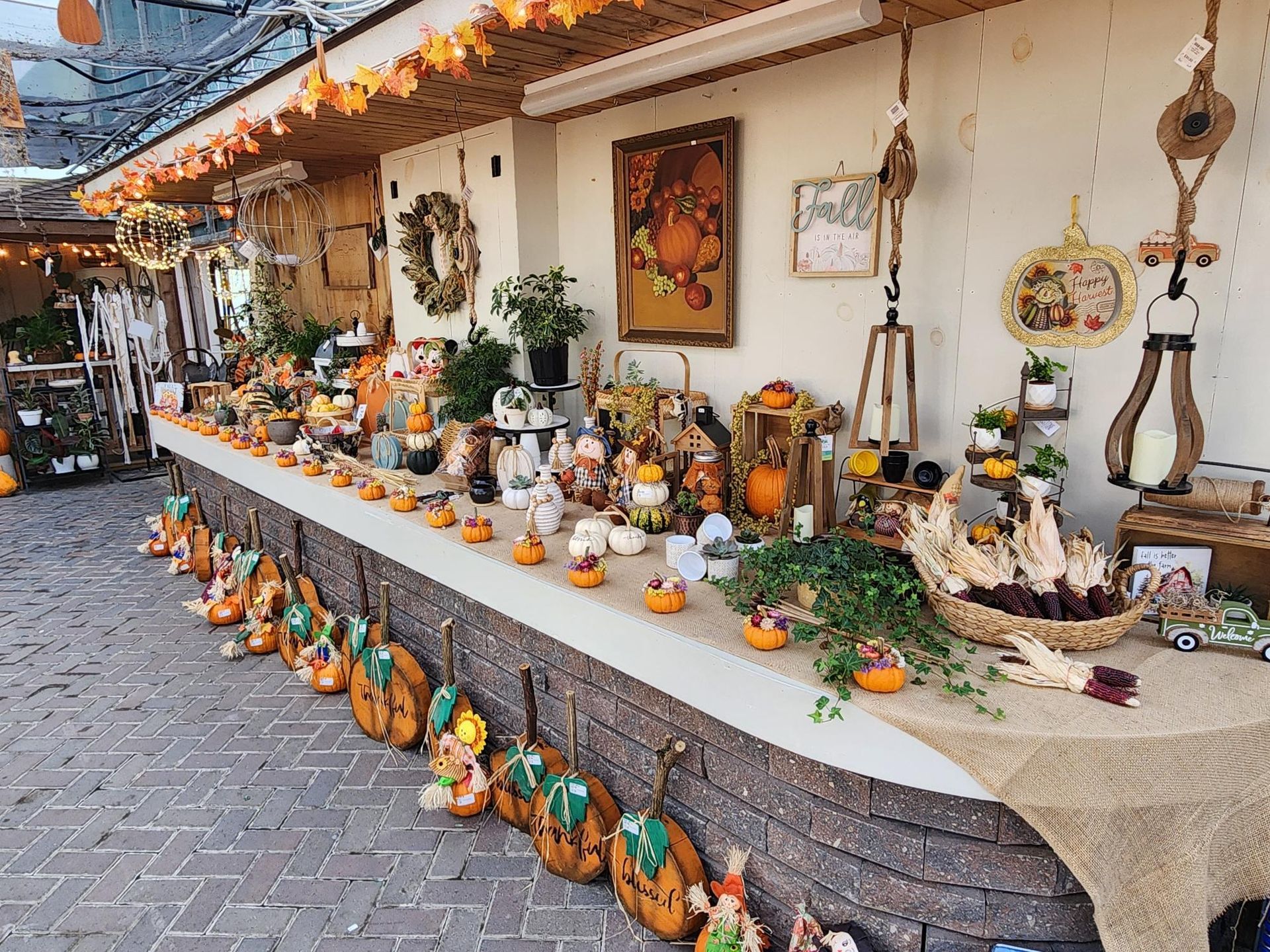 Decorated outdoor market stall with pumpkins, gourds, and autumn crafts displayed on tables and ground