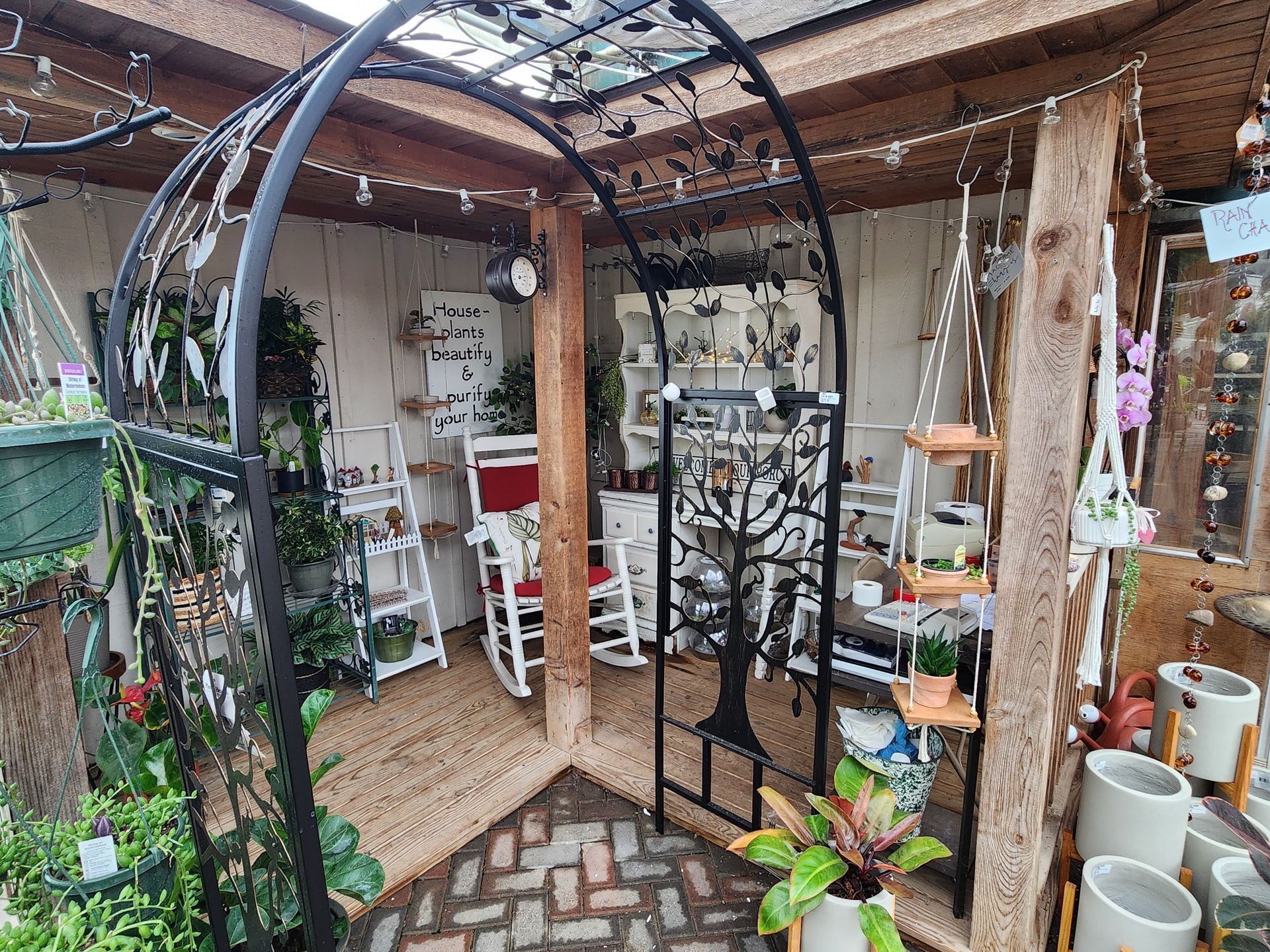 Indoor plant shop with arched metal trellis, white shelves, and potted plants on display