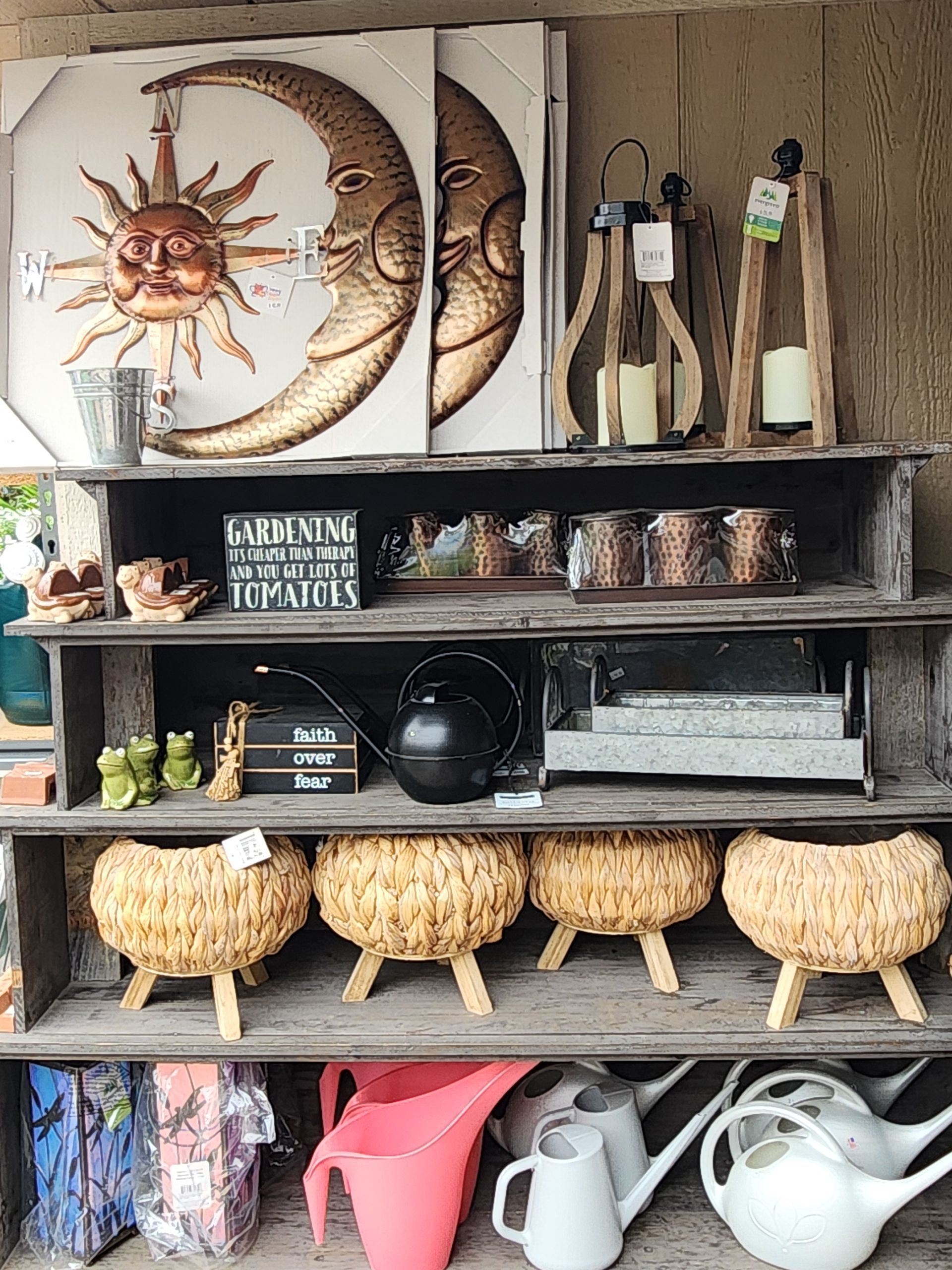 Rustic display shelf with decorative moon art, pottery, woven baskets, and white watering cans