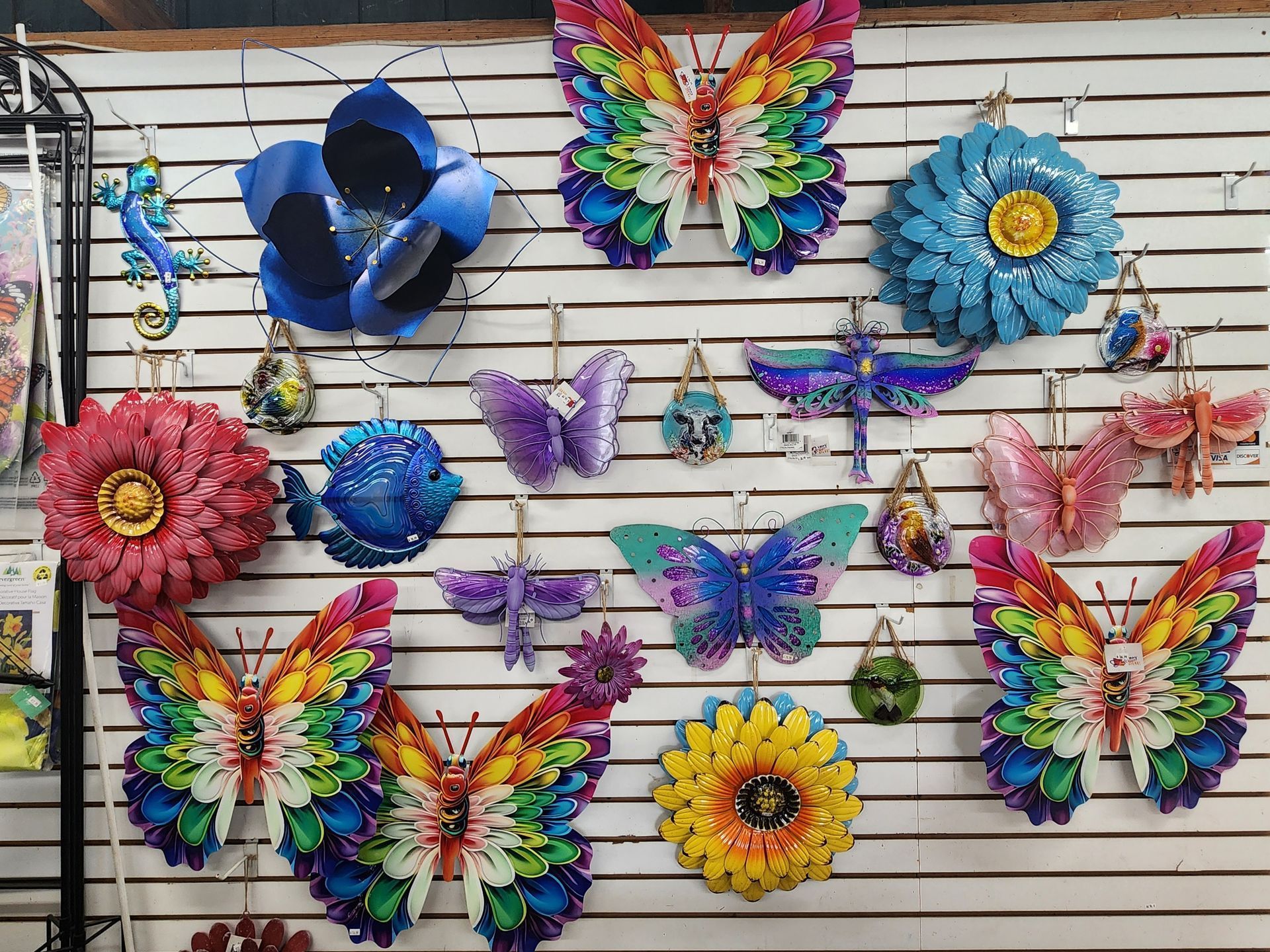 Colorful butterfly and flower wall art displayed on a slatwall grid