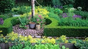 Colorful flower garden with potted plants around a tree and a cobblestone path