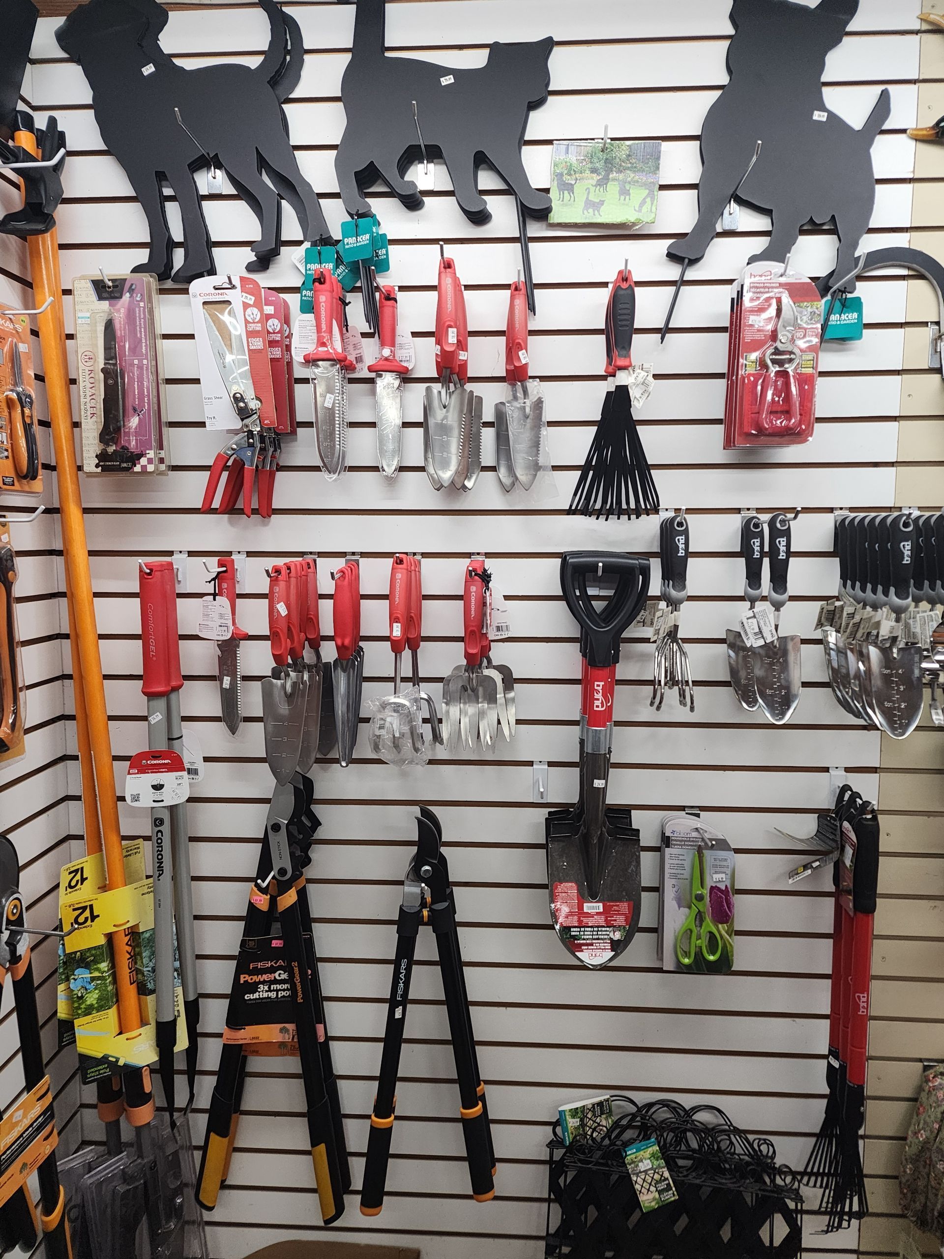 Wall-mounted display of pet grooming tools and leashes on white slatwall, with dog-shaped silhouettes above.
