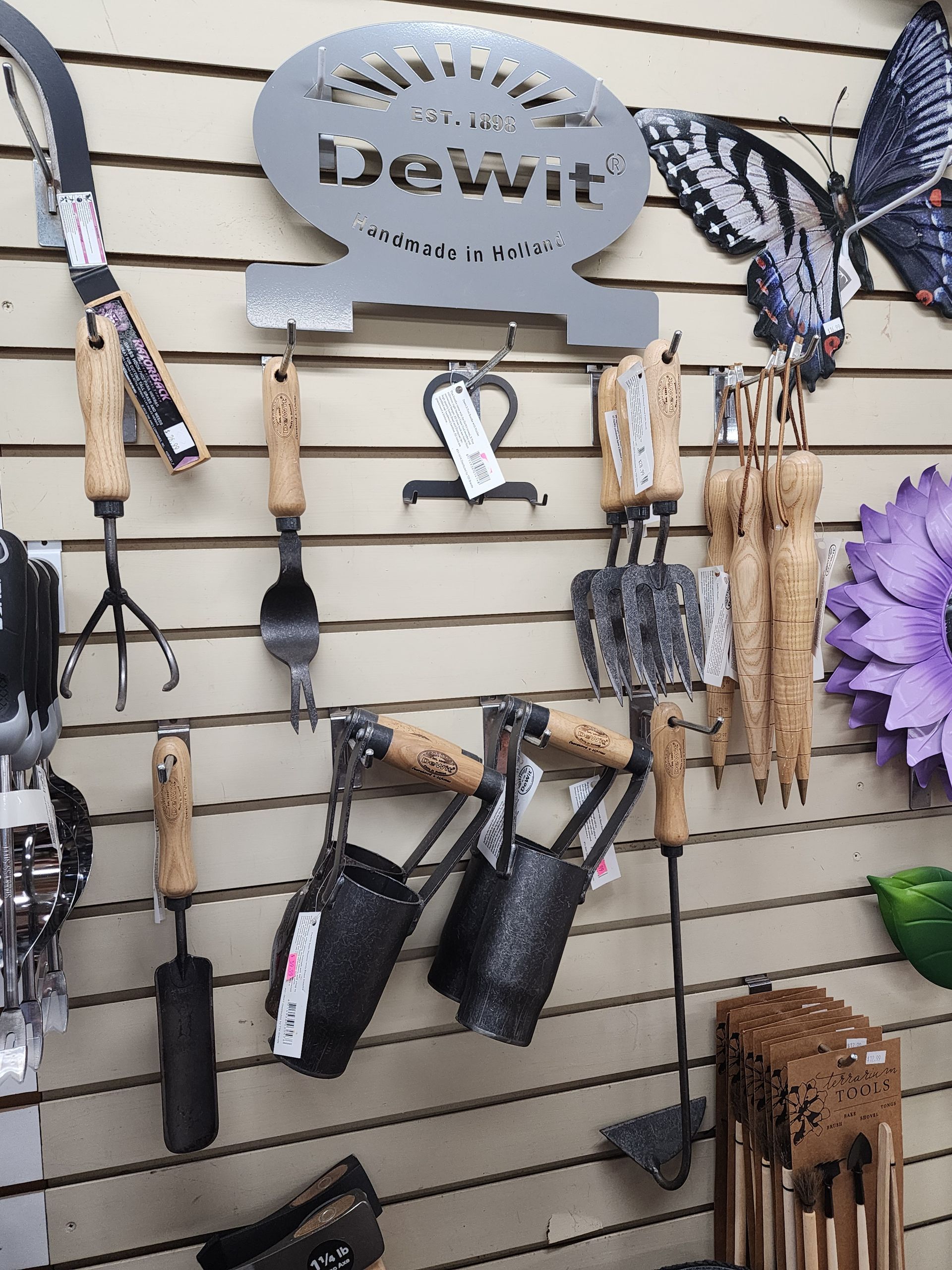 Assorted pet accessories and leashes hanging on a slatwall display with a “Devitt” sign