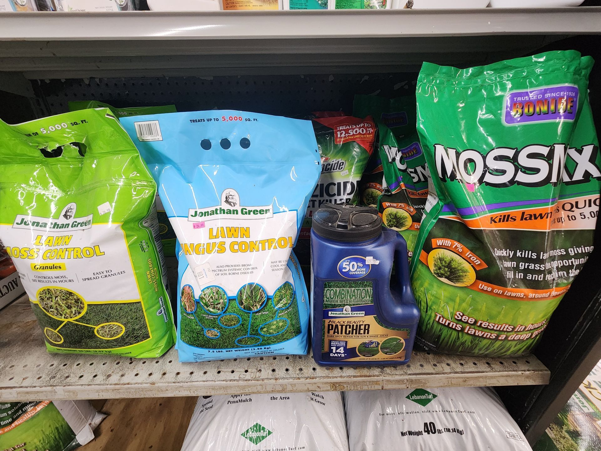 Shelf with assorted garden fertilizer bags and plant nutrient bottles in green, blue, and black packaging