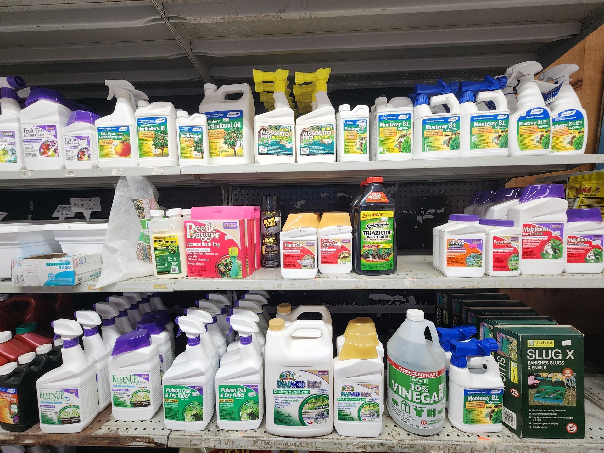 Shelves of assorted garden and household chemical jugs and spray bottles in a store aisle
