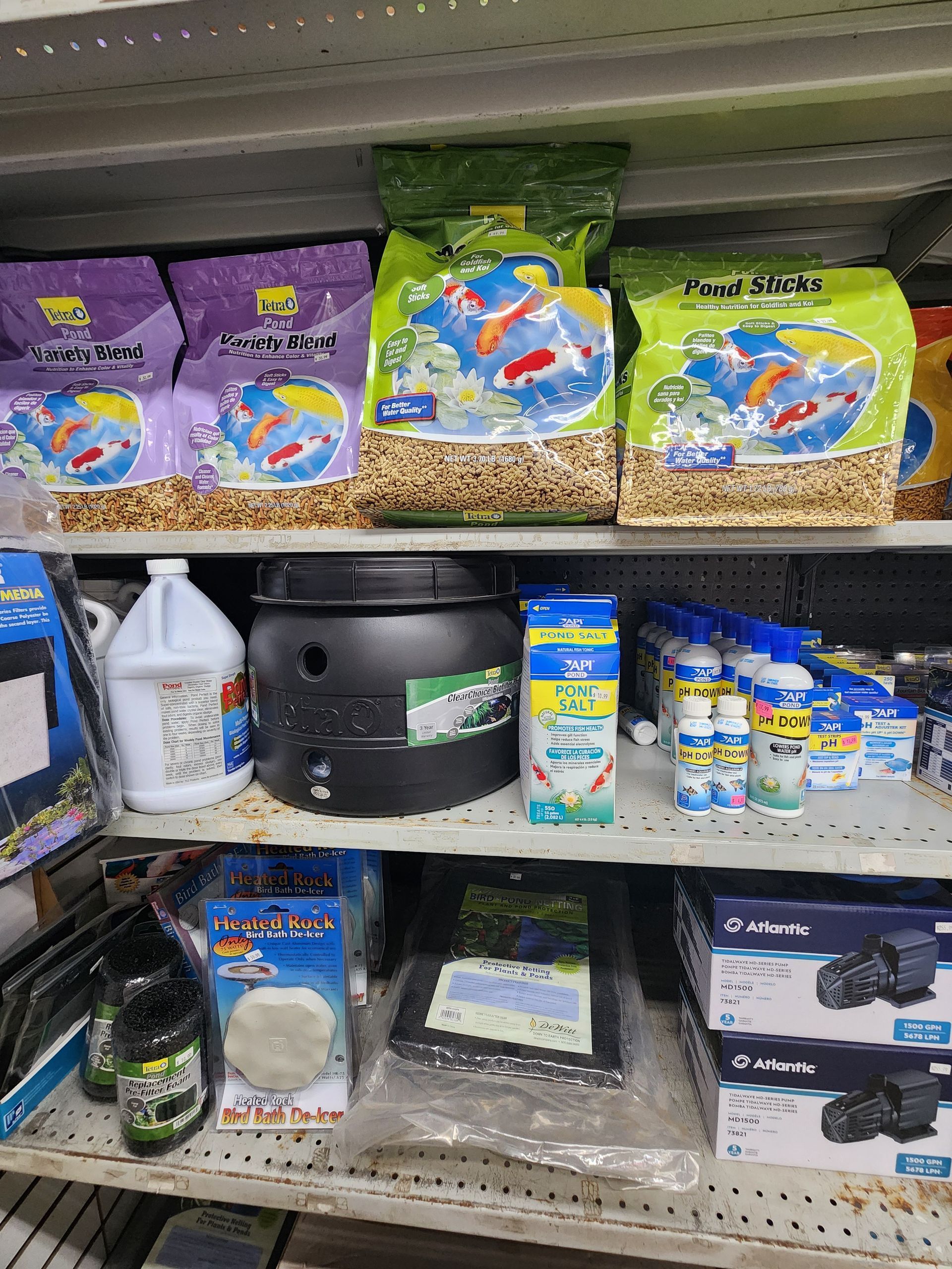 Shelf of aquarium supplies and fish food bags in purple, green, and blue packaging.