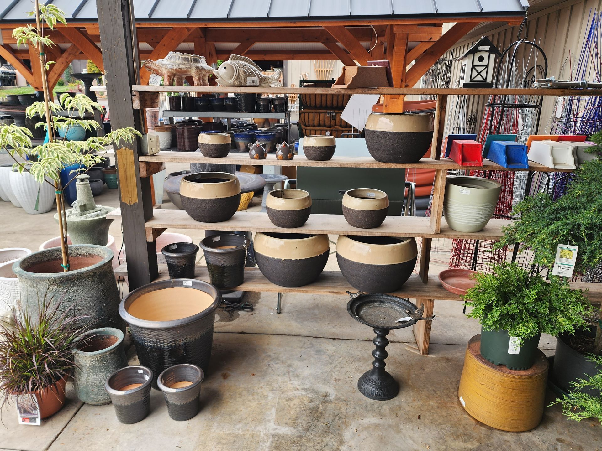Outdoor display of assorted large ceramic planters and garden pots on shelves and stands