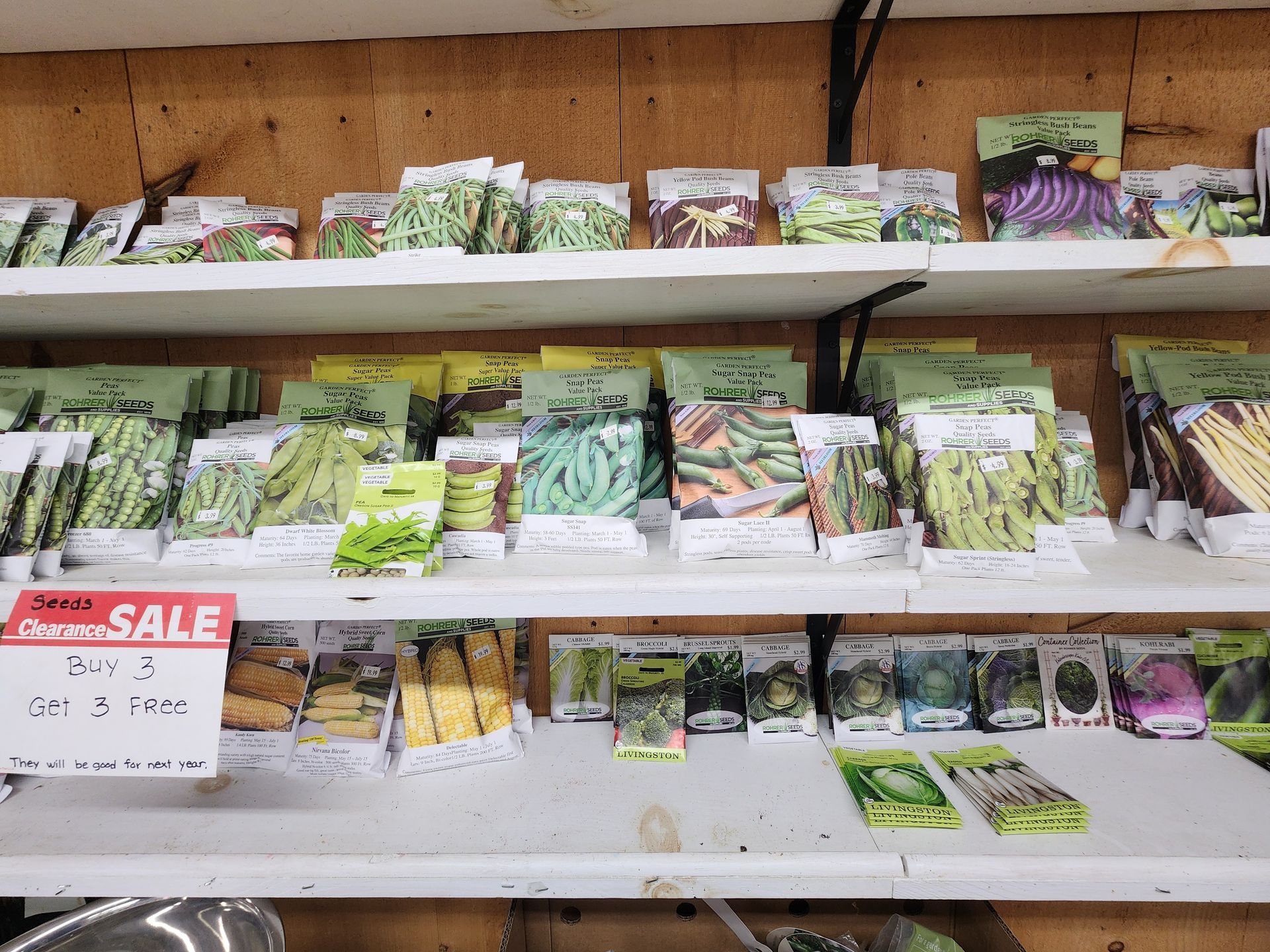 Shelves of seed packets in a garden store, with a red sale sign on the lower left.