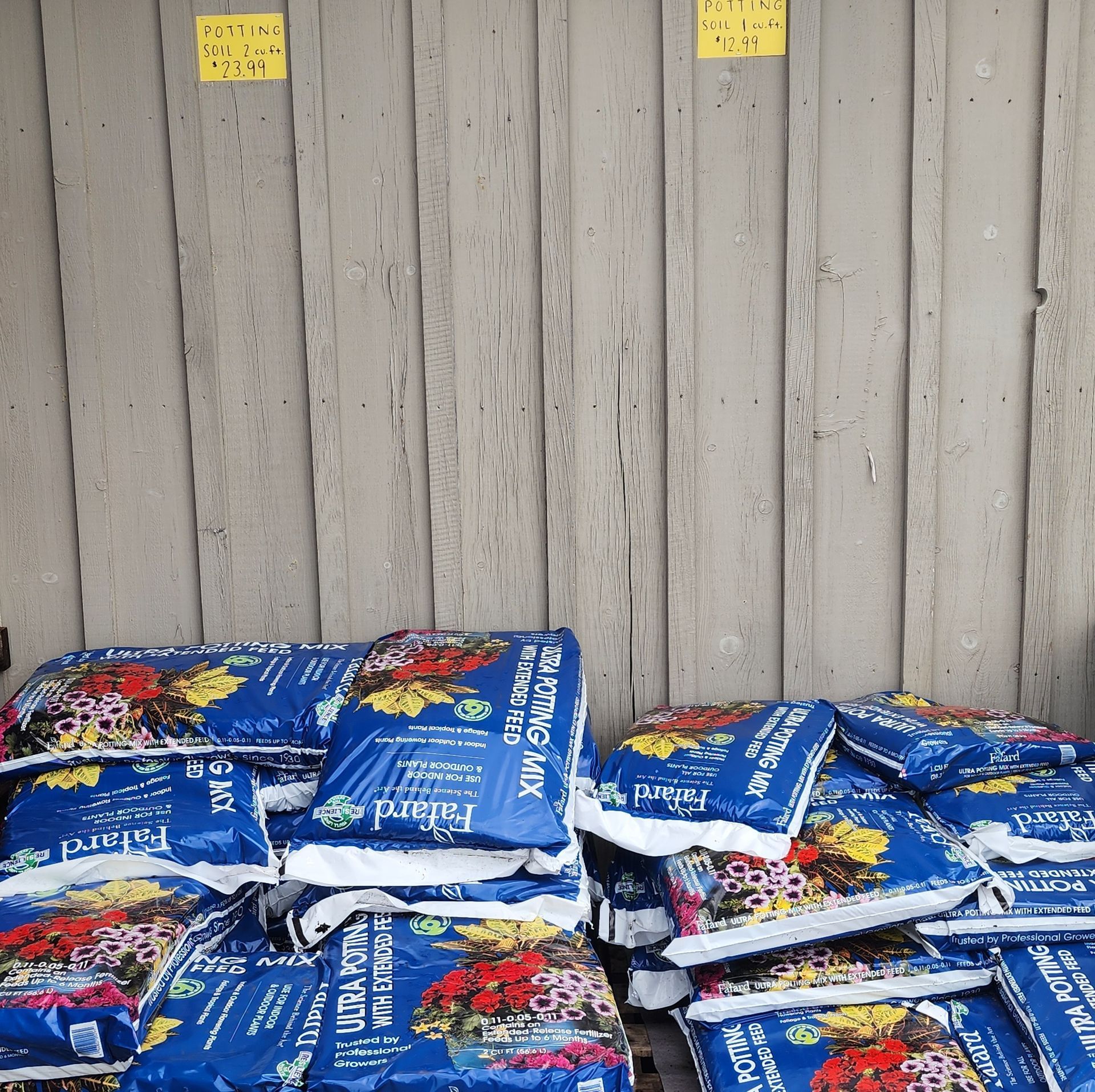 Stacked blue bagged goods piled against a wooden wall.