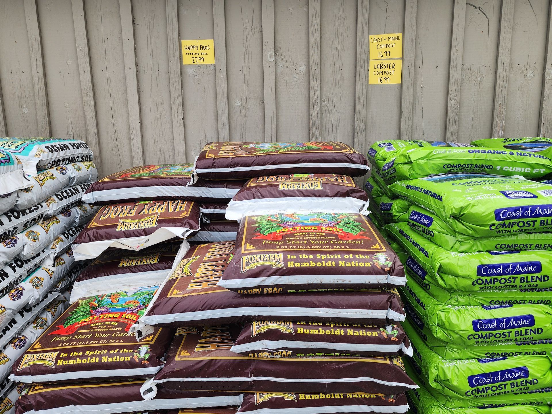 Stacks of bagged supplies in brown, white, and bright green packaging against a wall.