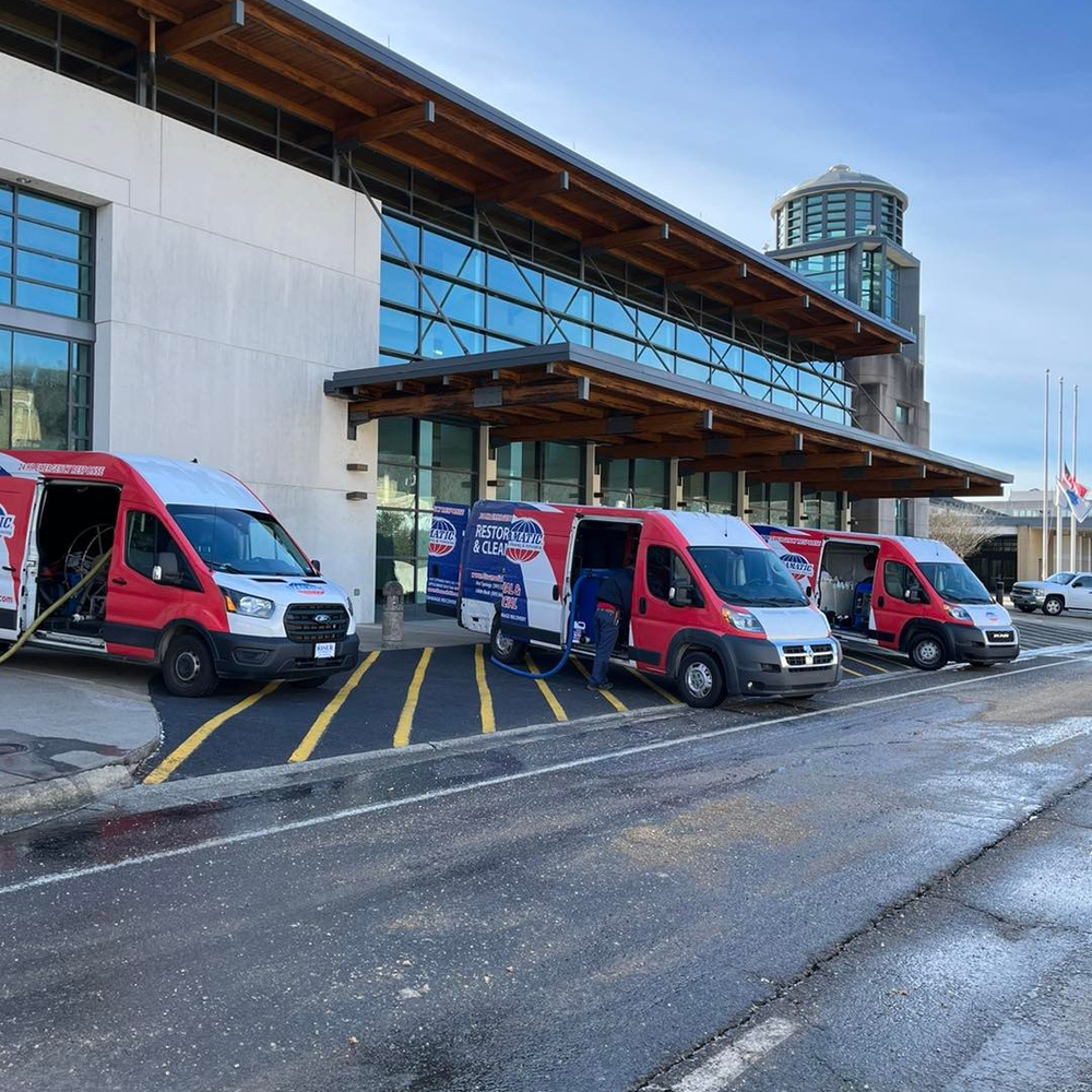 Red and white service vans parked in front of a modern building with glass windows. Workers are visible near the vans.