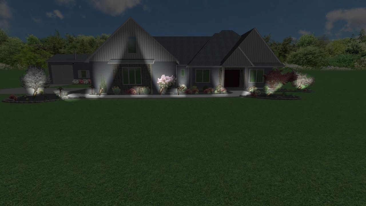 Night view of a modern house with outdoor lighting illuminating the exterior; surrounded by green grass.