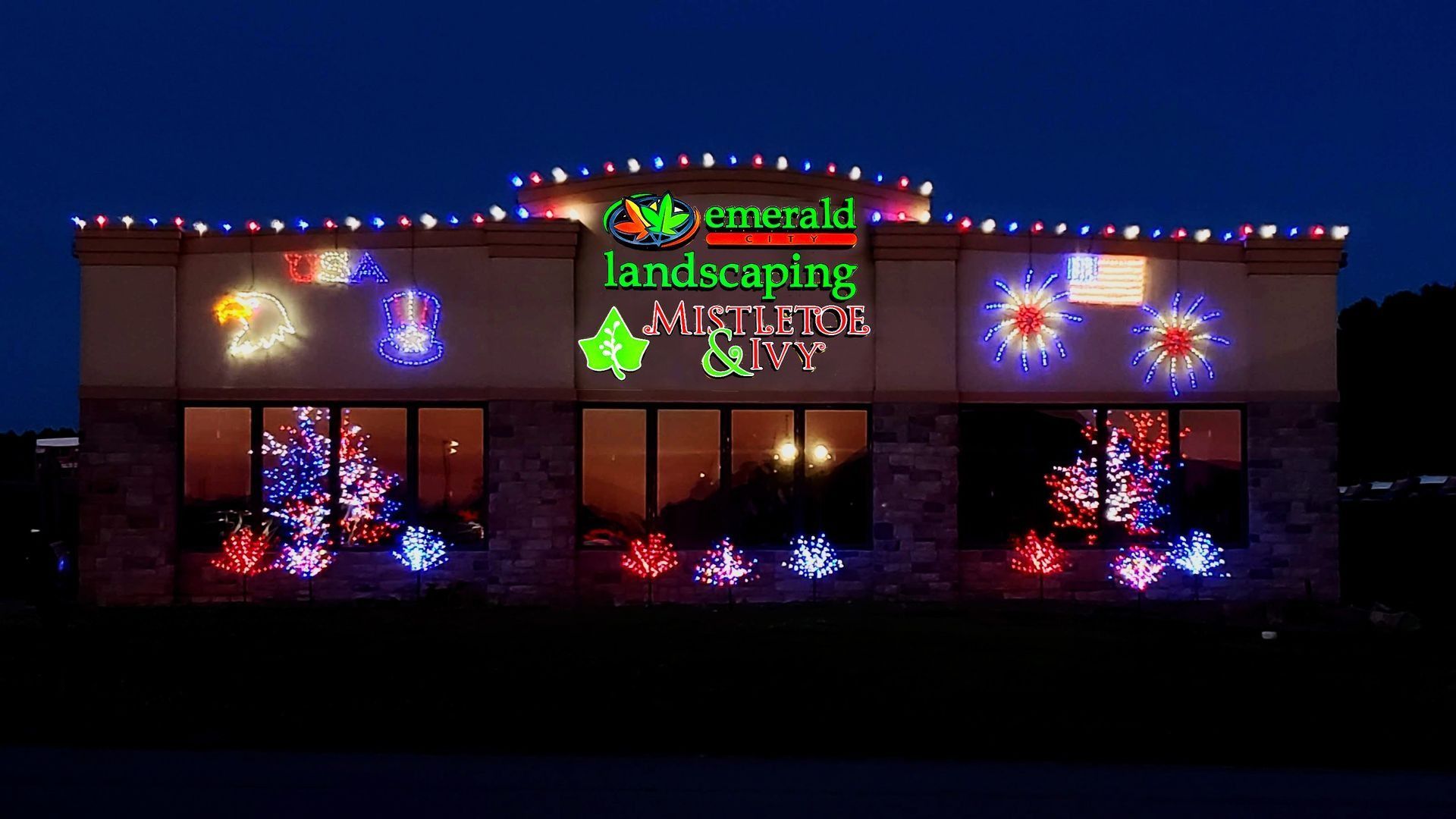 Emerald Landscaping business decorated with colorful holiday lights at night.