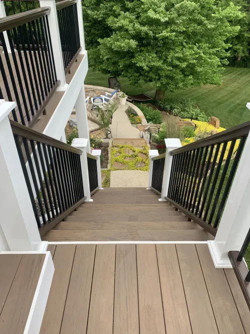 view of deck staircase from the top down. black railings with white posts.