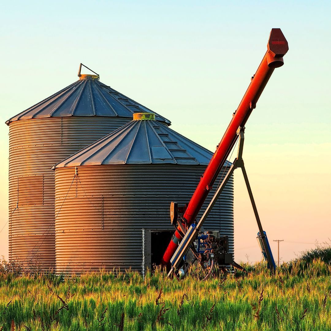 an orange grain augur sitting in front of a silo