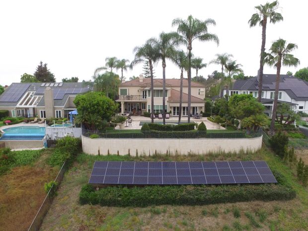 Residential homes with solar panels, palm trees, and a pool in a sunny neighborhood