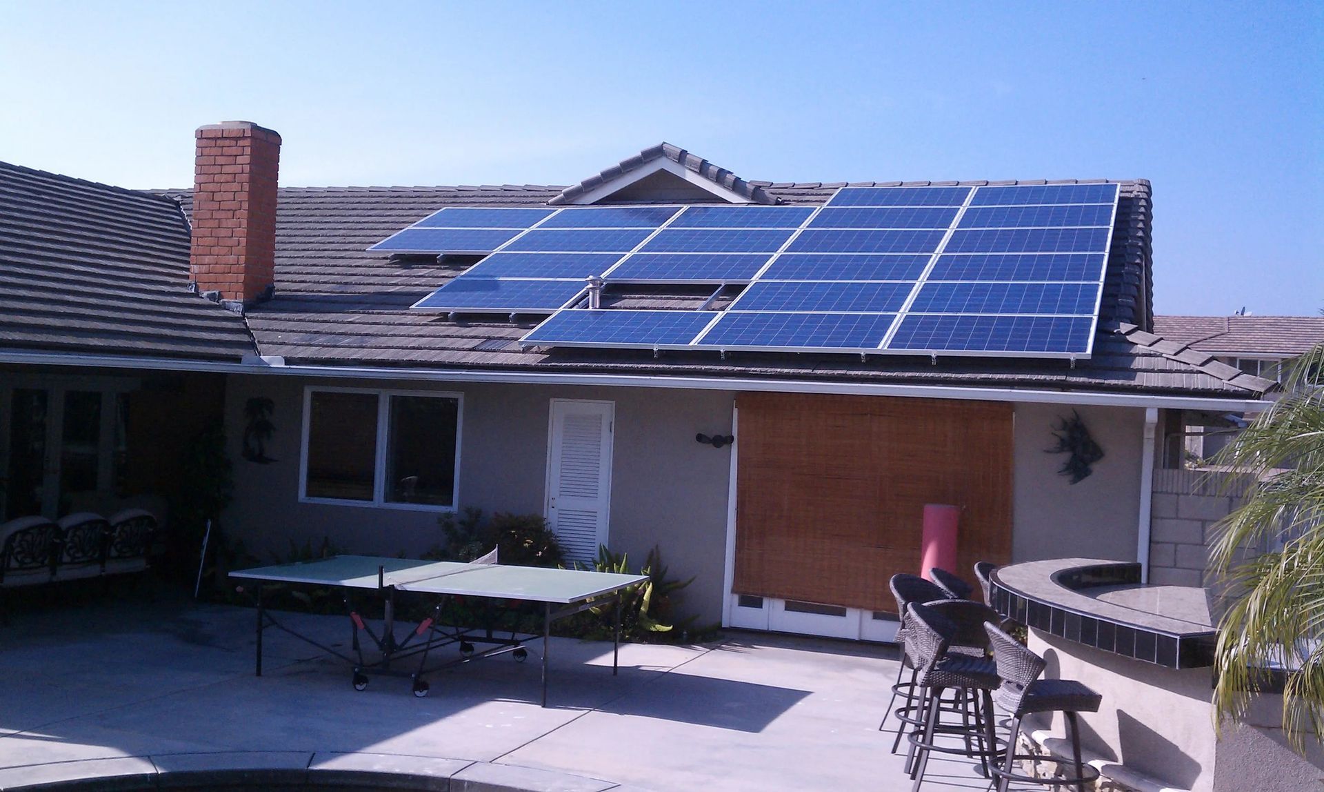 House roof with blue solar panels in a sunny courtyard