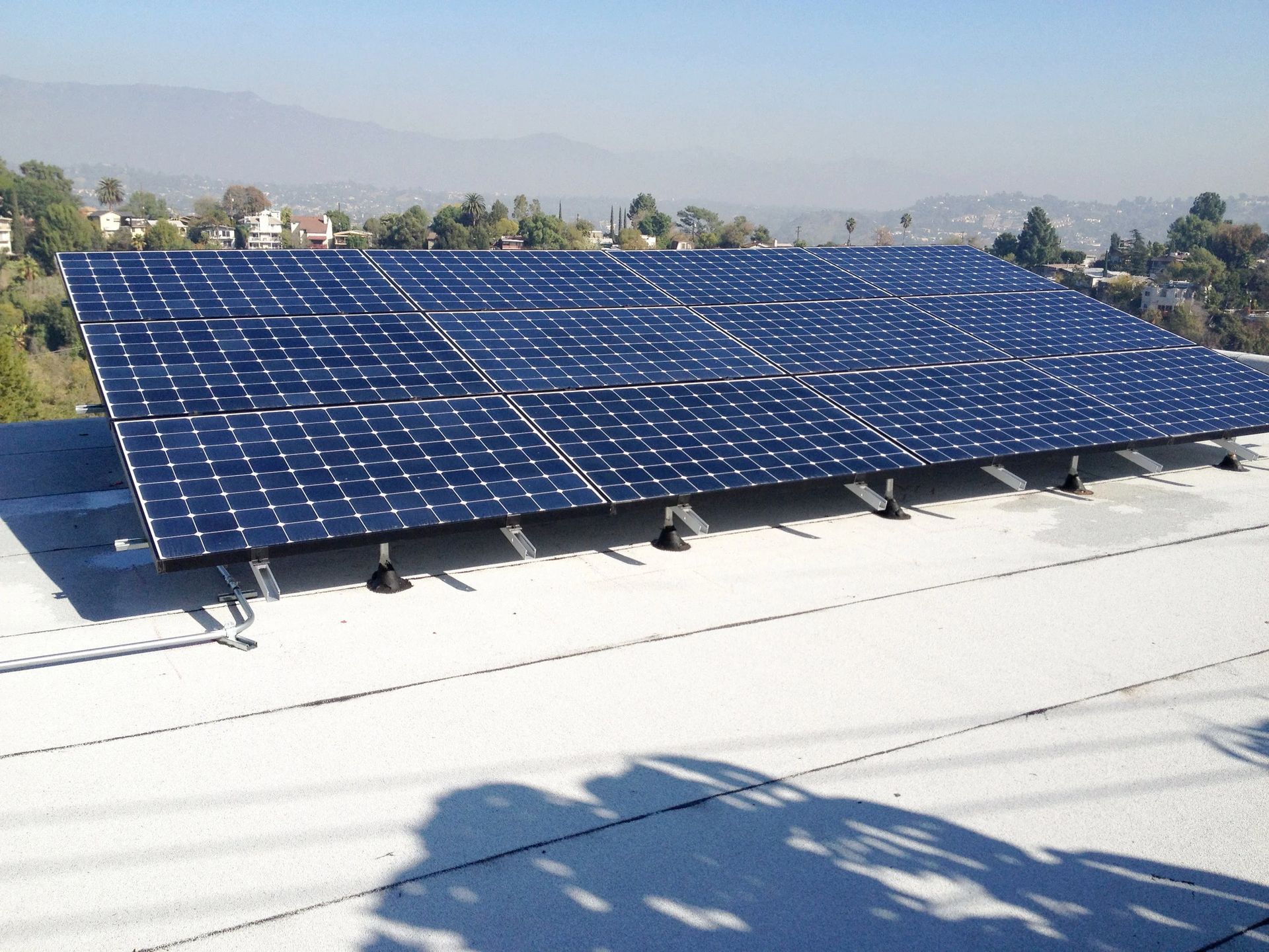 Blue solar panels on a rooftop with mountains in the background