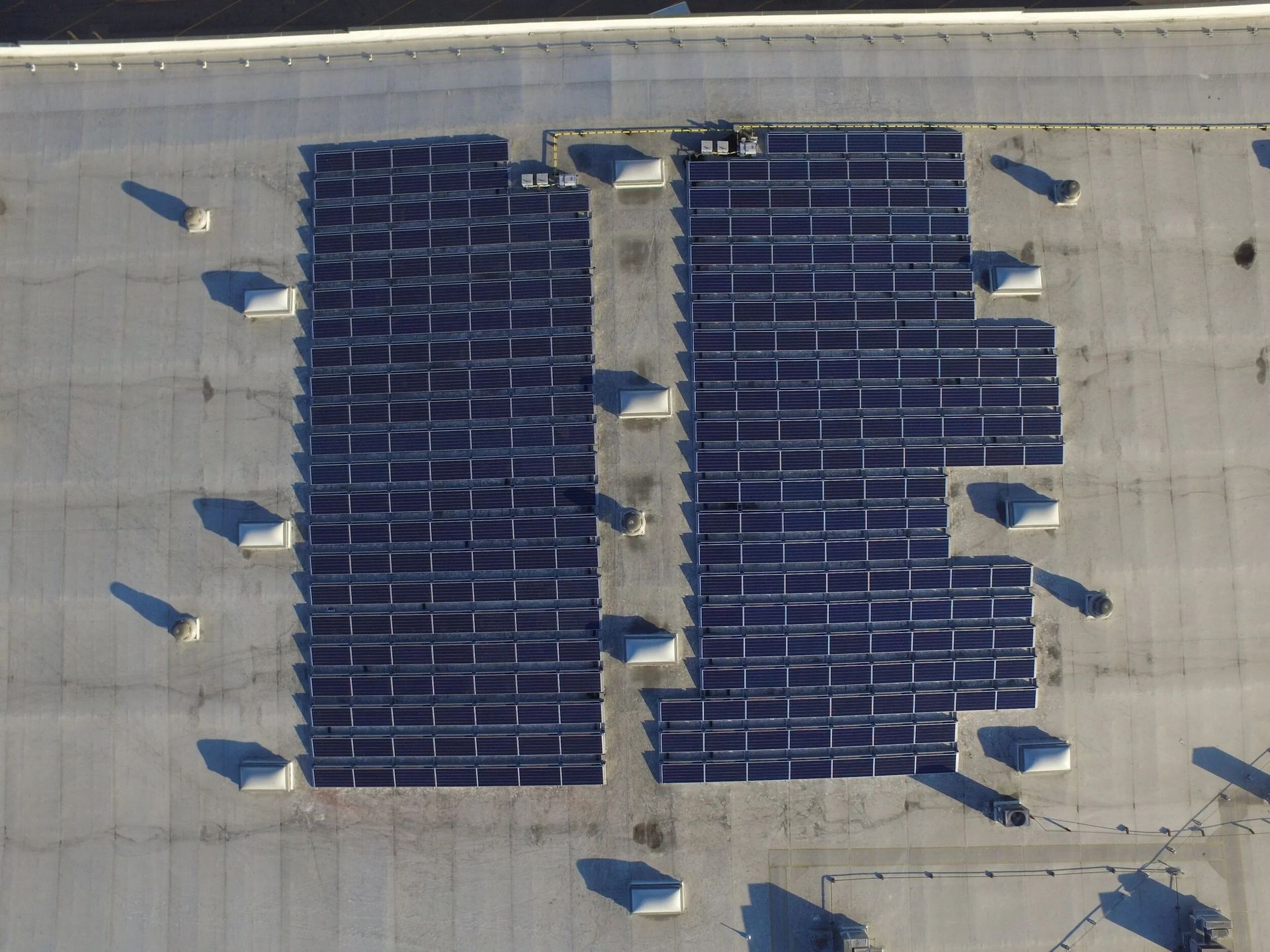 Rooftop solar panel arrays installed in two blocks on a flat gray roof.