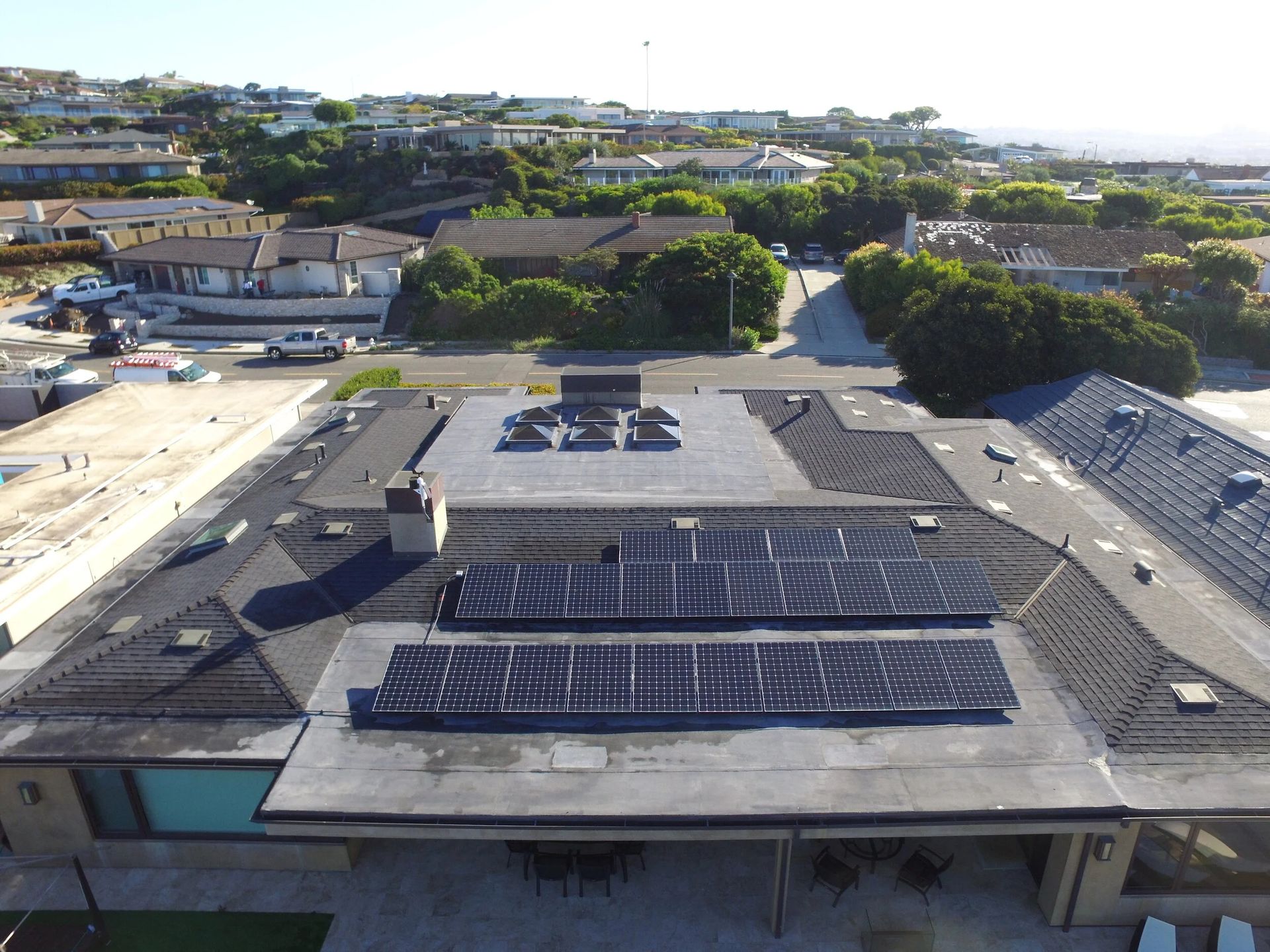 Rooftop with solar panels on a large building, viewed from above in daylight.