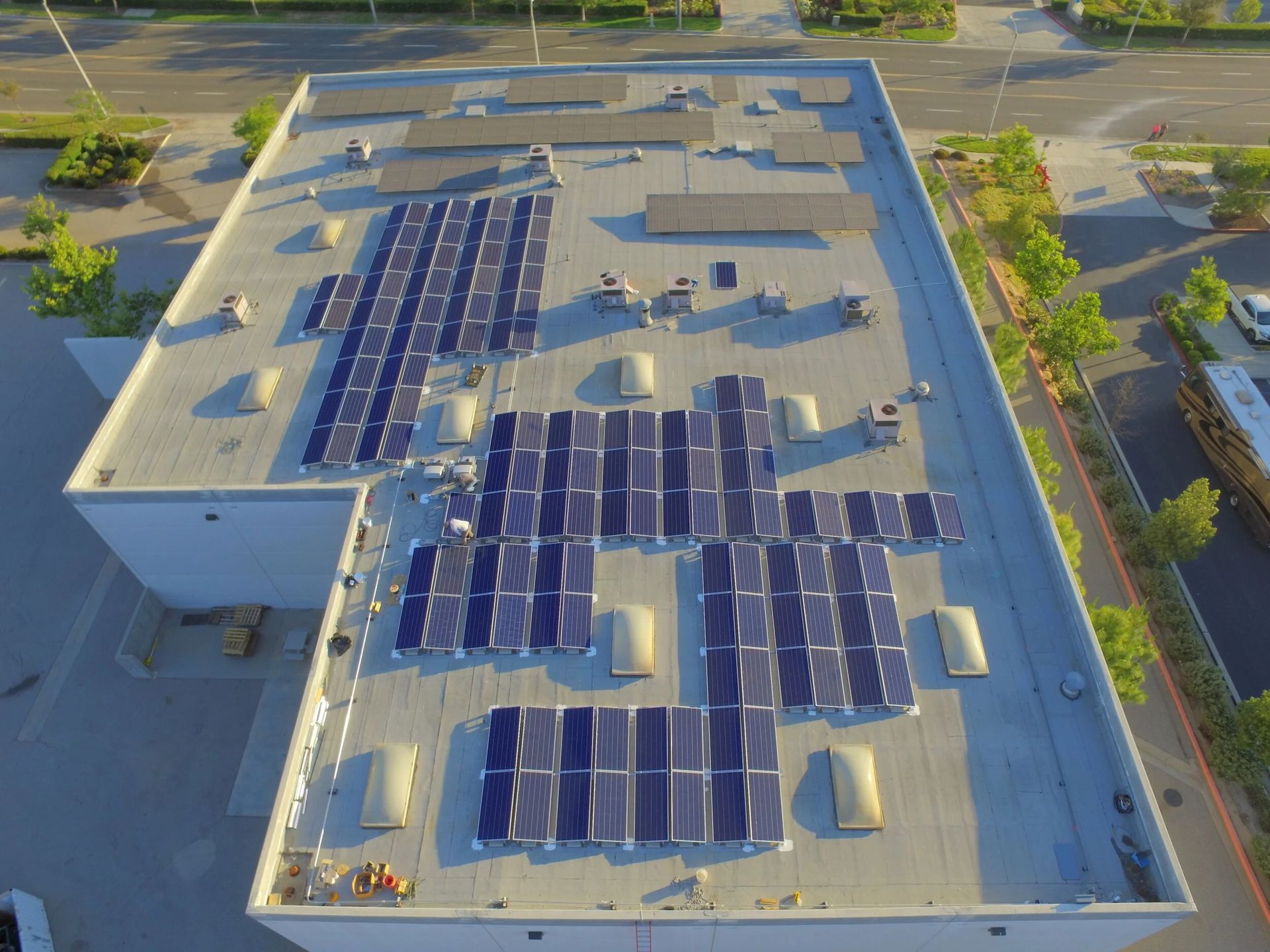 Aerial view of a building rooftop covered with solar panels in a parking lot area