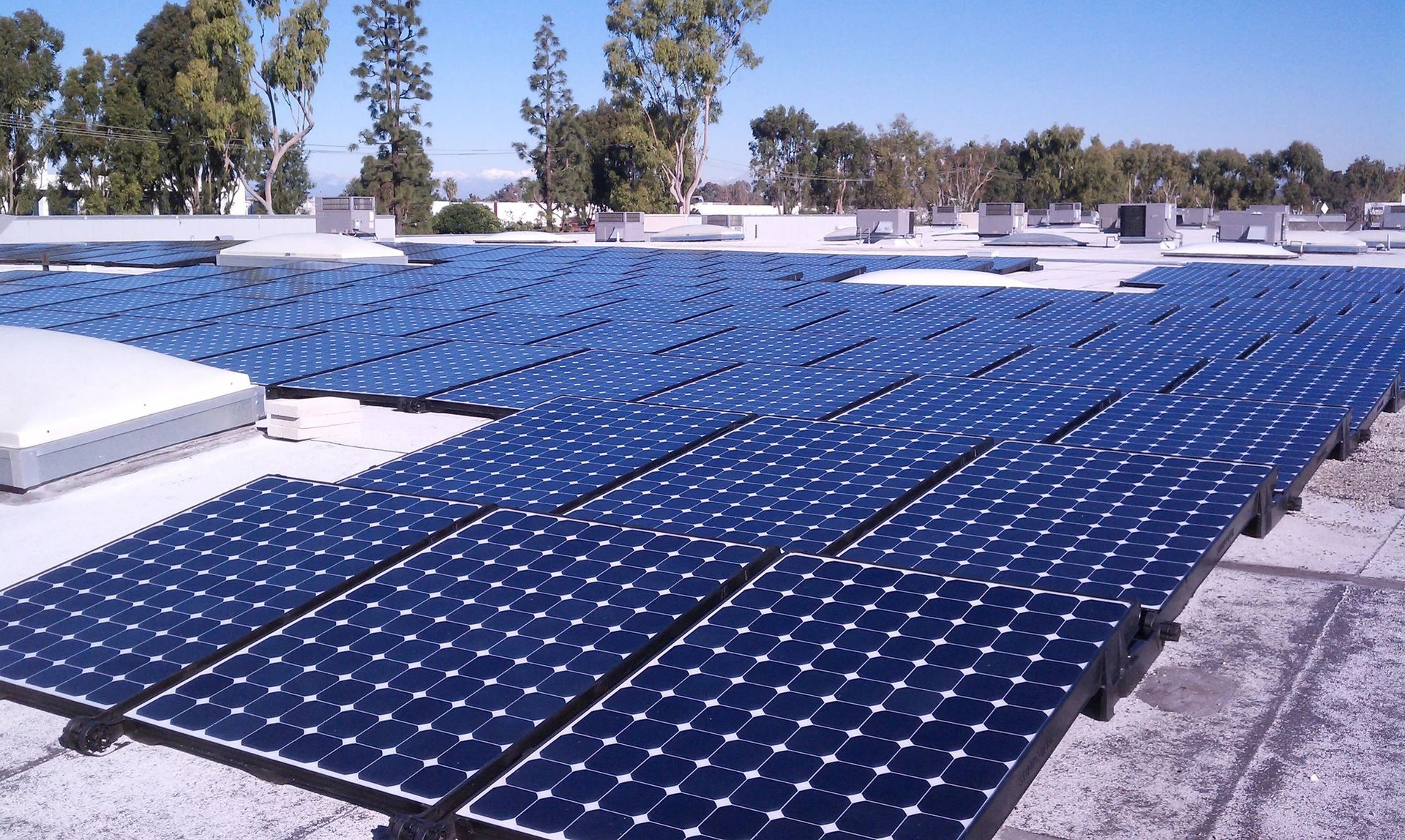 Blue solar panels on a rooftop under a clear sky