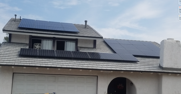 House with solar panels on the roof and a garage below, viewed from the front.