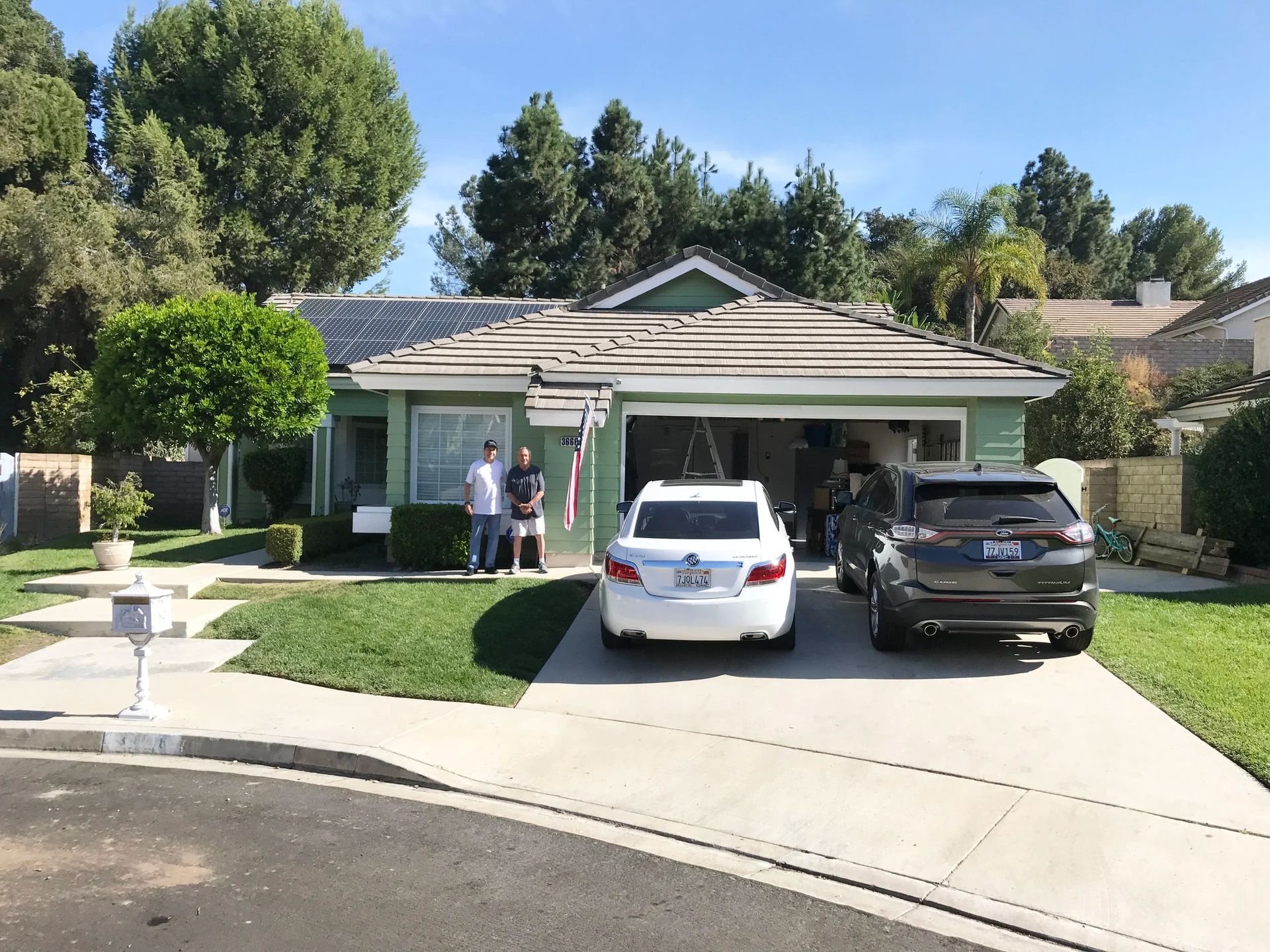 Suburban house with two cars in the driveway and a person standing by the front door