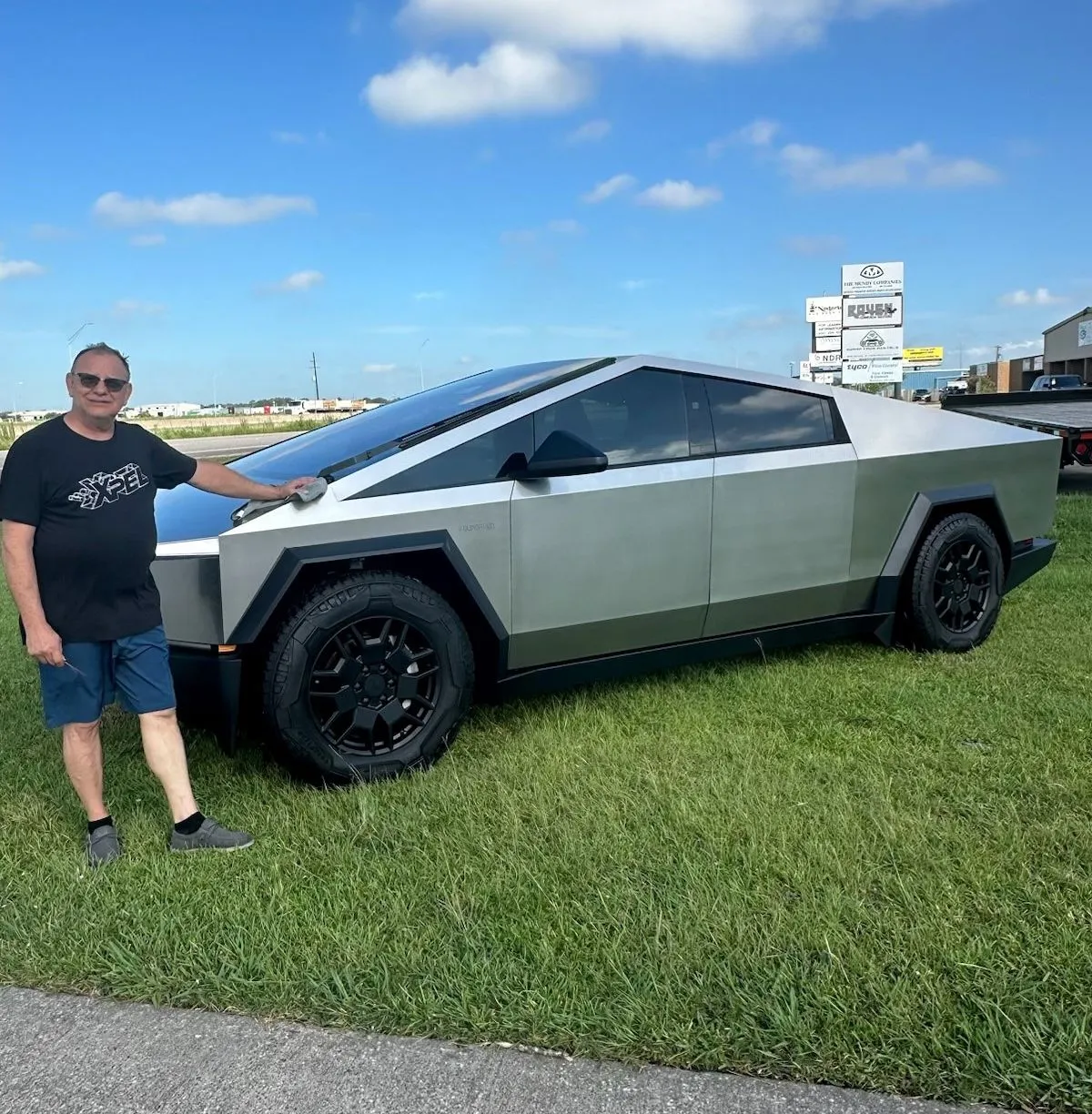 A man is standing next to a tesla cybertruck.