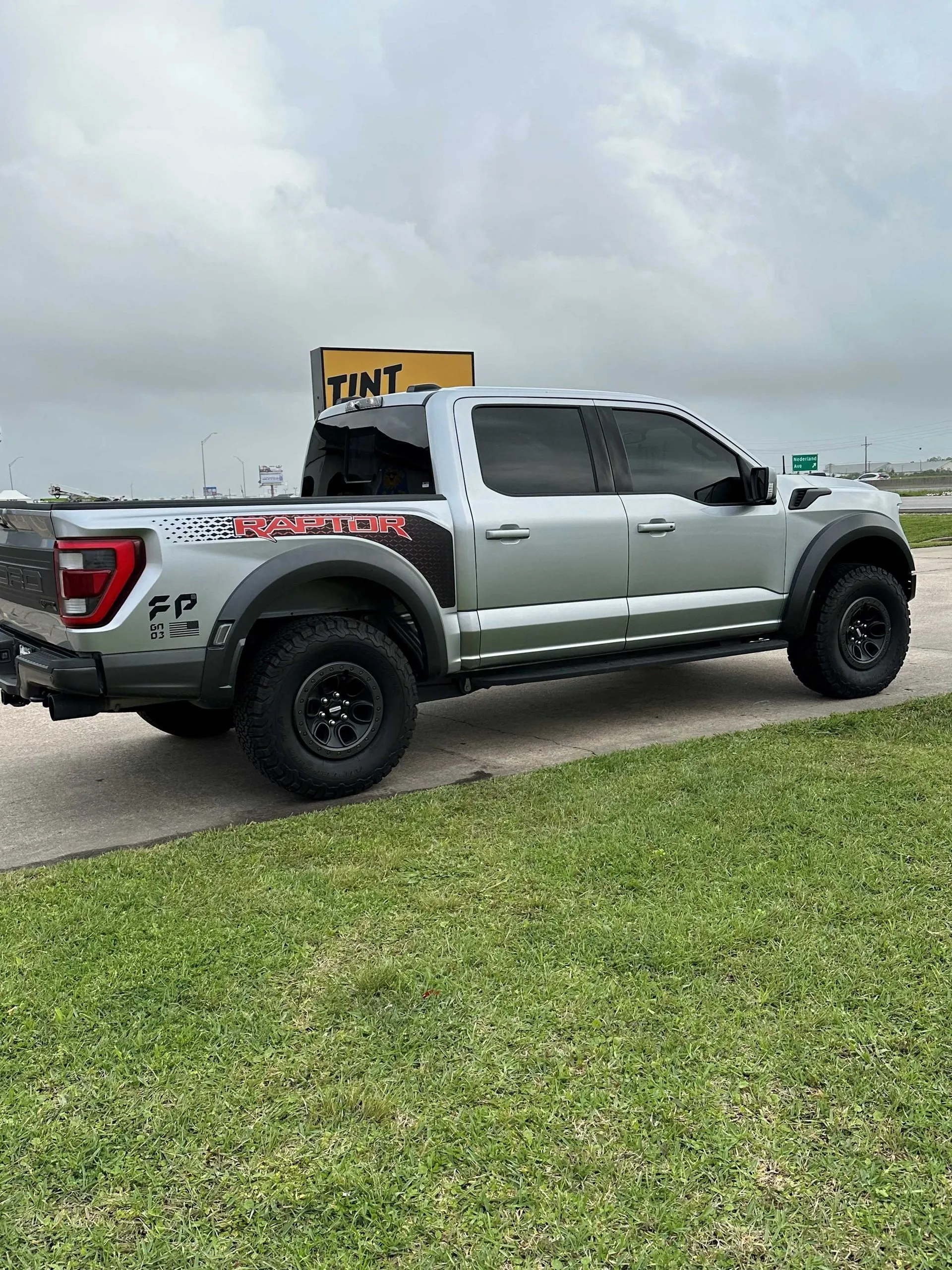 A silver pickup truck is parked on the side of the road next to a grassy field.