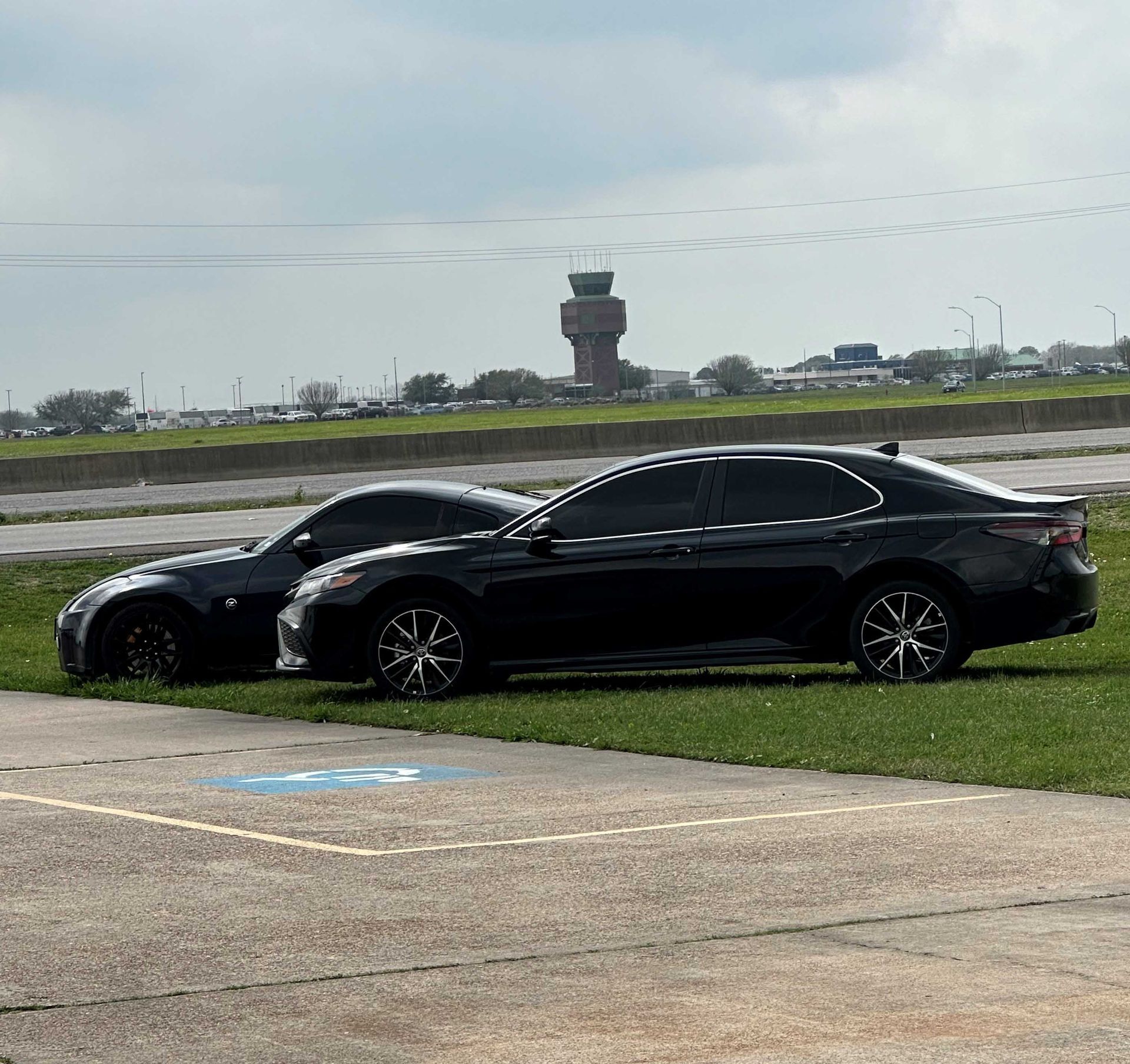 Two black cars are parked next to each other in a parking lot